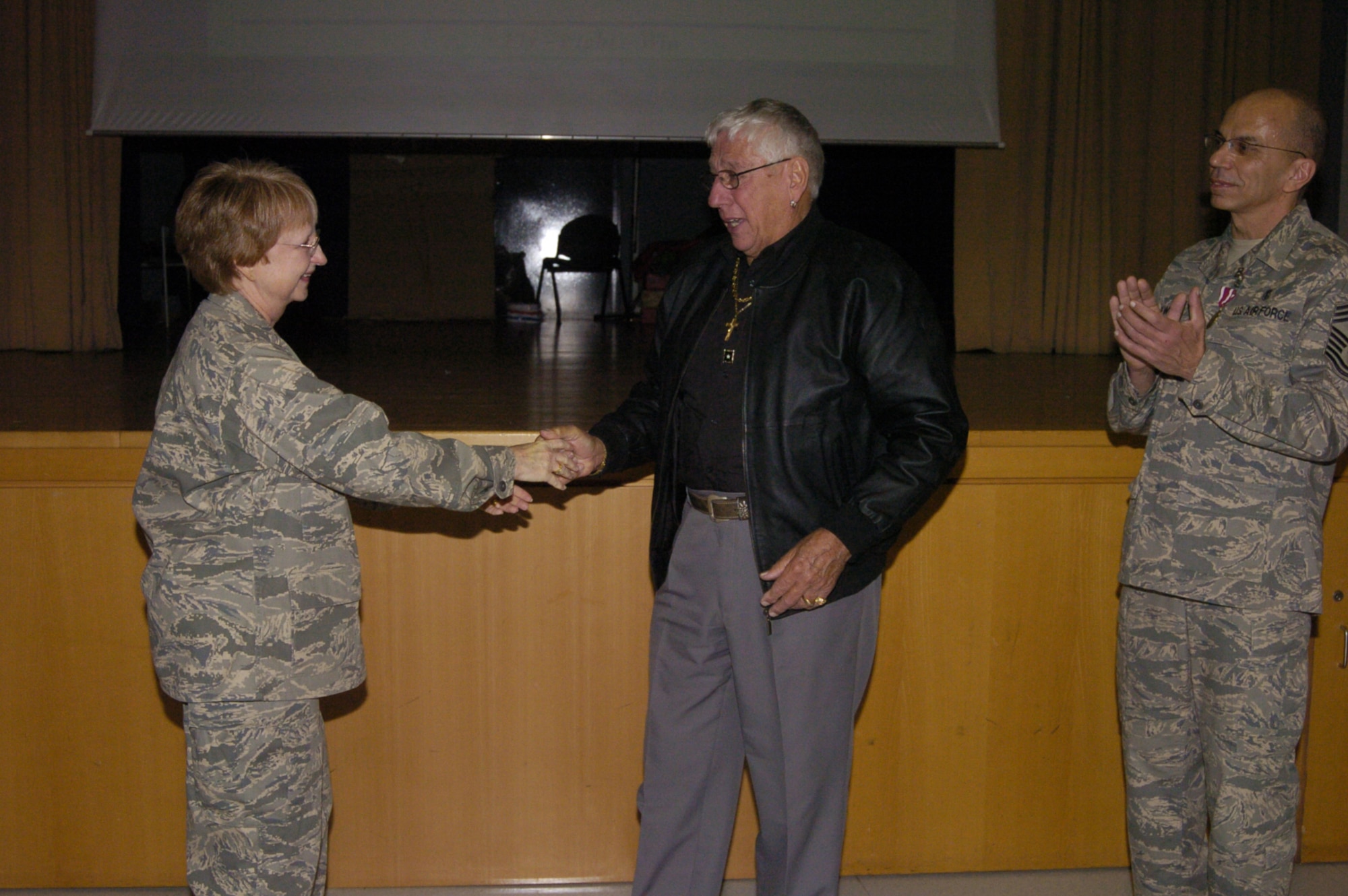 Major Gen. Melissa Rank, the Assistant Air Force Surgeon General for Nursing Services and Medical Force Development,  presents her personal coin to Herman Lewis, the father of Chief Master Sgt. David Lewis (right) the enlisted advisor to the Assistant Air Force Surgeon General for Nursing Services. (U.S. Army Photo/Chuck Roberts)
