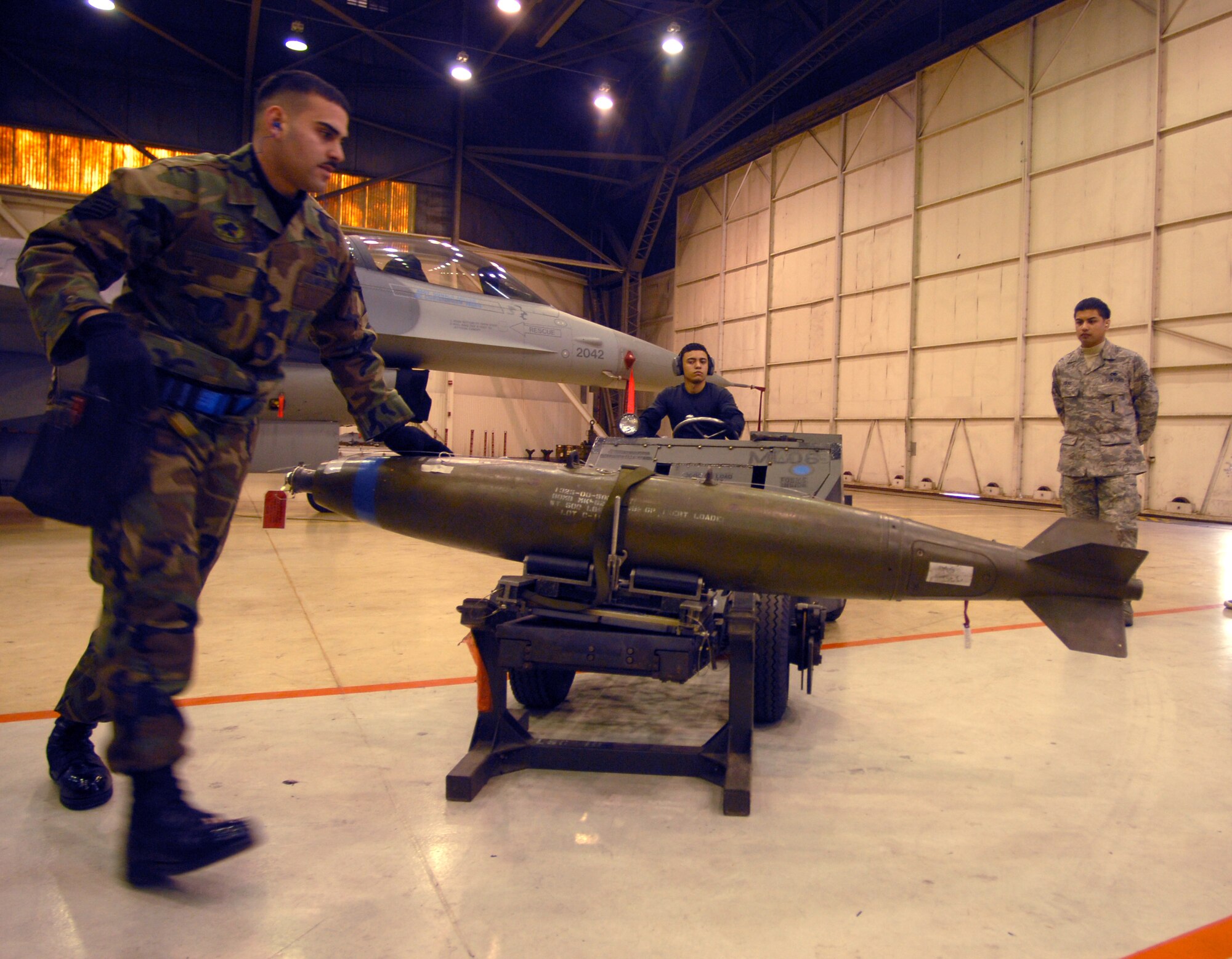 KUNSAN AIR BASE, South Korea -- Staff Sgt. Danny Colon (foreground) and Airman First Class Jay Maldonado (back left), both from the 8th Aircraft Maintenance Squadron, prepare to move a bomb into position during the weapons load competition as Senior Airman Erwin Viray judges here Dec. 14.  This was the final weapons load competition between the 80th and 35th Fighter Squadrons for 2007.  (U.S. Air Force photo/Senior Airman Steven R. Doty)