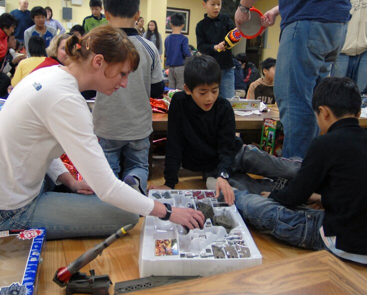KAE JONG, South Korea -- Technical Sgt. Catherine Lobbestael plays with children from Kae Jong orphanage during an Airmen Committed to Excellence (A.C.E.) sponsored Christmas party here Dec. 15.  Tech. Sgt. Lobbestael along with other Airmen from Kunsan Air Base spent the afternoon handing out gifts, coloring, eating, and playing with children during the visit.  8th Fighter Wing Airmen donated various gifts to include beanie babies by 8th Communications Squadron and a Play Station 2 by A.C.E.  (U.S. Air Force photo/Senior Airman Steven R. Doty)