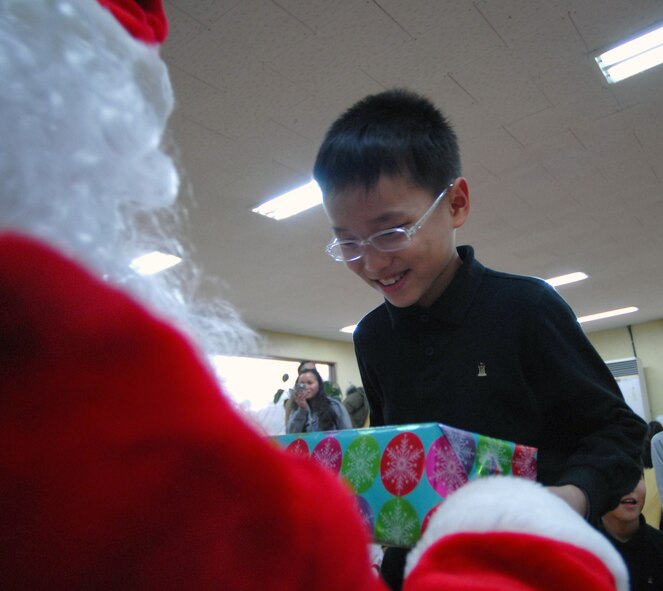 KAE JONG, South Korea -- Technical Sgt. John Craven, Santa, hands out a gift to a Kae Jong orphan here Dec. 15.  Airmen from Kunsan Air Base spent the afternoon handing out gifts, coloring, eating, and playing with children during an Airmen Committed to Excellence (A.C.E.) sponsored trip.  8th Fighter Wing Airmen donated various gifts to include beanie babies by 8th Communications Squadron and a Play Station 2 by A.C.E.  (U.S. Air Force photo/Senior Airman Steven R. Doty)