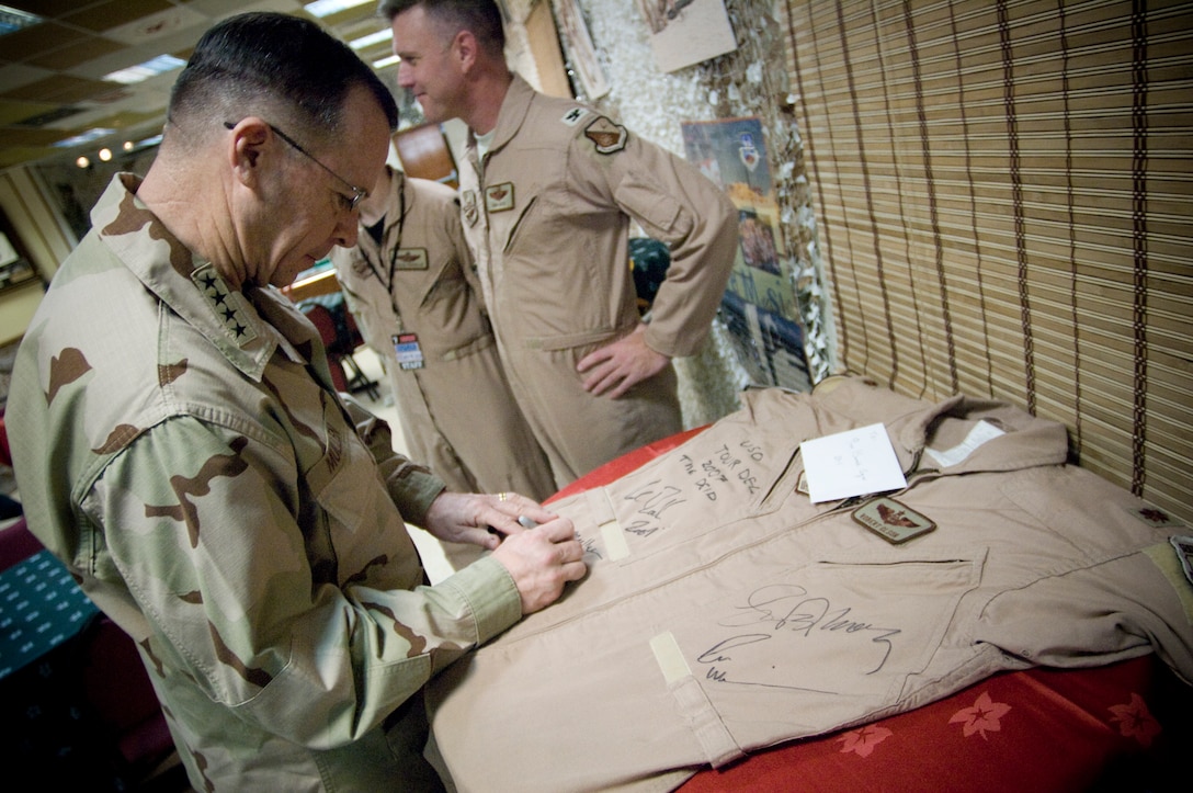 Chairman of the Joint Chiefs of Staff Navy Adm. Mike Mullen autographs a flight suit prior to hosting the USO Holiday Tour, at Qatar, Dec. 17, 2007. 