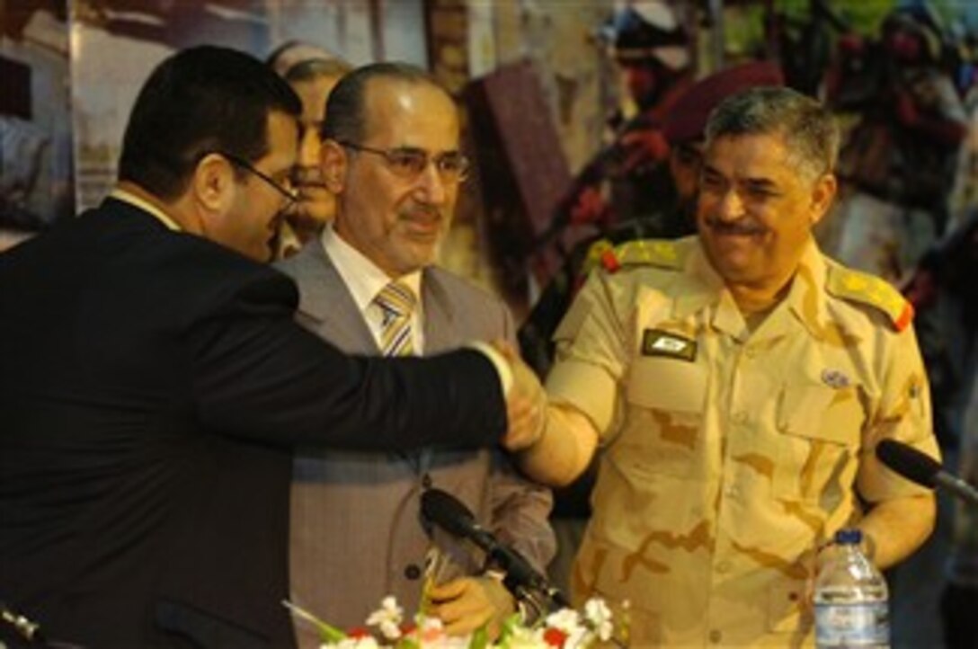 Muhammad al-Wa'ili, left, the governor of Basra, and Iraqi army Gen. Mohan al-Furaiji, the commander of the Basra Operations Center, shake hands as Iraqi National Security Advisor Muwafaq al-Rubaie looks on during a ceremony in Basra, Iraq, Dec. 16, 2007, to hand over security responsibility of the Basra province from British to Iraqi forces. 