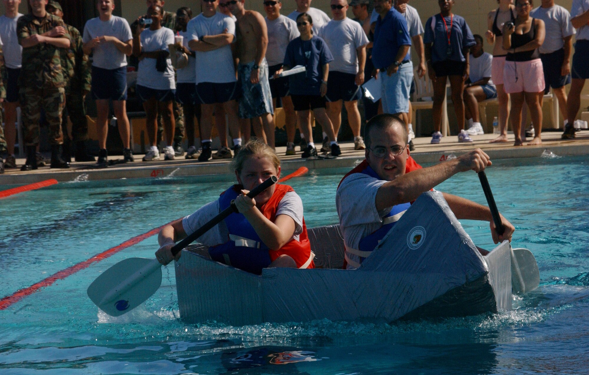 Staff Sgt David Andrews and Airman 1st Class Cheri Alsip, both from the 393rd EBS, pilot their creation dubbed USS Fat Chance toward the finish line in the cardboard boat race here during Team Andersen Challenge December 14. The participants were required to make their craft from nothing but cardboard and duct tape. Sergeant Andrews and Airman Alsip finished third overall and were surprised their vessel showed very little signs of leakage or water damage. However, both Airmen opted not to trade their wings for sails, retired Fat Chance after the voyage, and declined all offers to test Fat Chance in the Pacific Ocean. (Air Force photo/Tech. Sgt. Steven Wilson) 