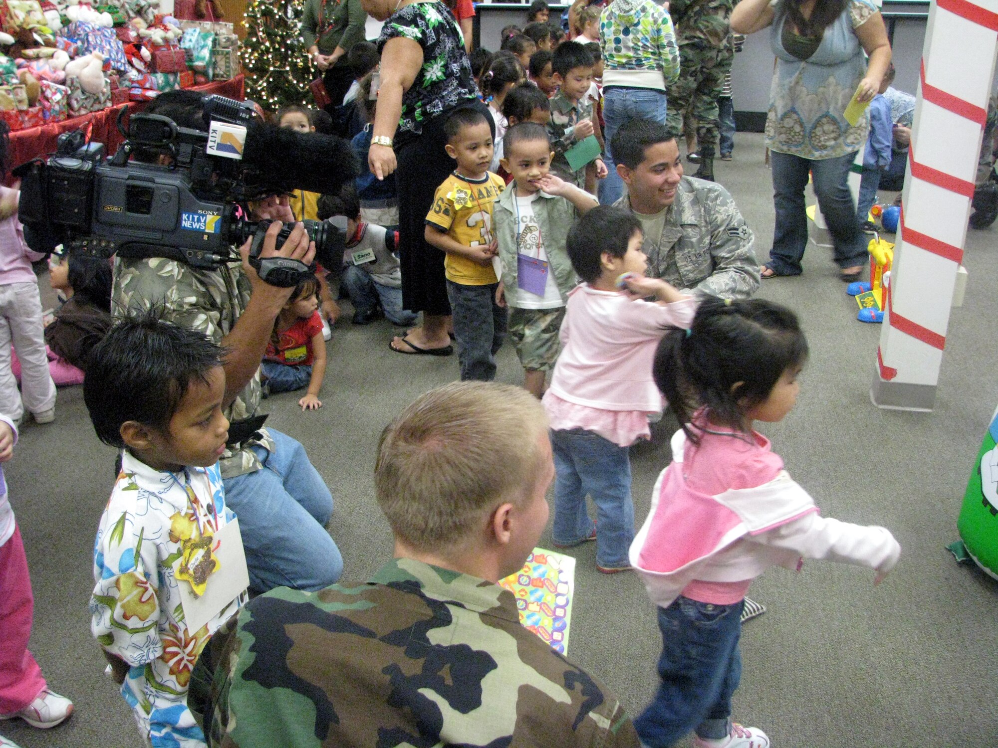 Airman 1st Class Daniel Gamboa, 15th Communications Squadron, helps children with the ball toss game during the Head Start hhristmas party , hosted by the 15th Mission Support Group here. The group raised money through various fundraisers to put together a holiday party complete with gifts for the children as well as classroom supplies for the teachers. Photo by Staff Sgt Erin Smith