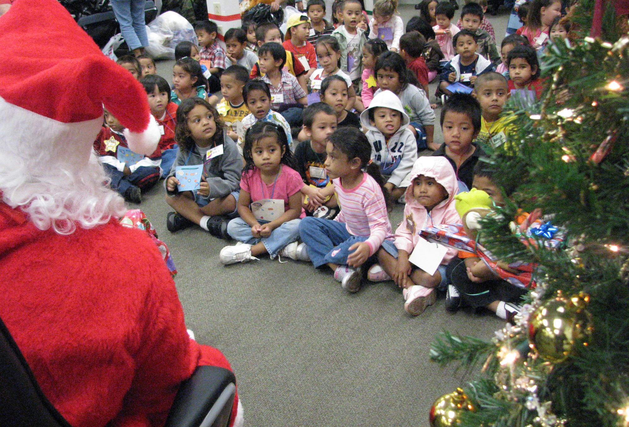 Santa hands out gifts to each of the children at the party. The 15th Mission Support Group raised enough money to buy each child a gift. Toys for tots matched the MSG’s donation so each child received 2 gifts and a stuffed animal.  Photo by Staff Sgt. Erin Smith