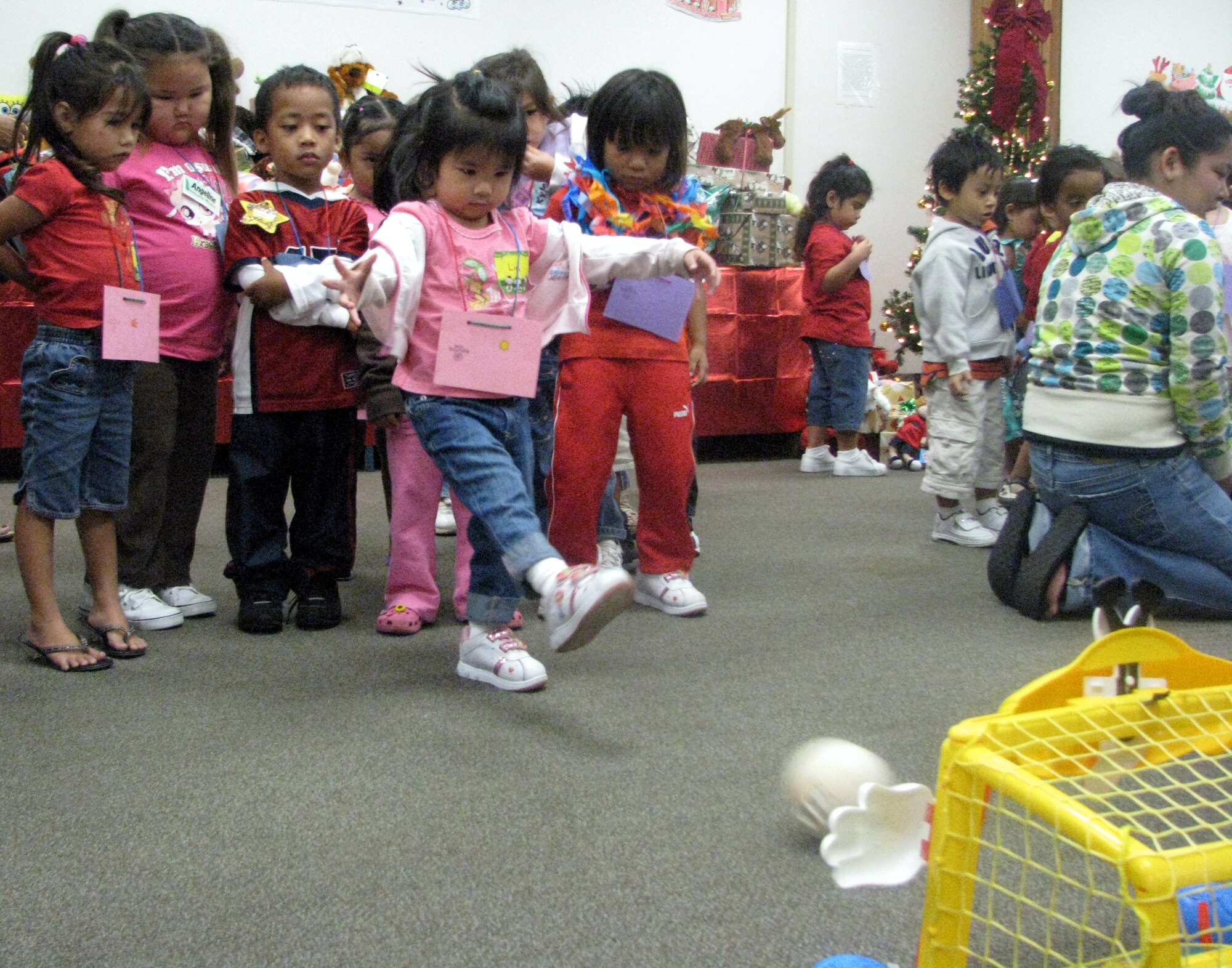Lia kicks a ball into a basket during one of the games at the holiday party. During the holiday party, Capt. Shelby Henry, 15th Logistics Readiness Squadron, and members from the 15th Mission Support Group hosted 100 children between the ages of 3 and 5 years old as well as Head Start staff members. Photo by Staff Sgt. Erin Smith