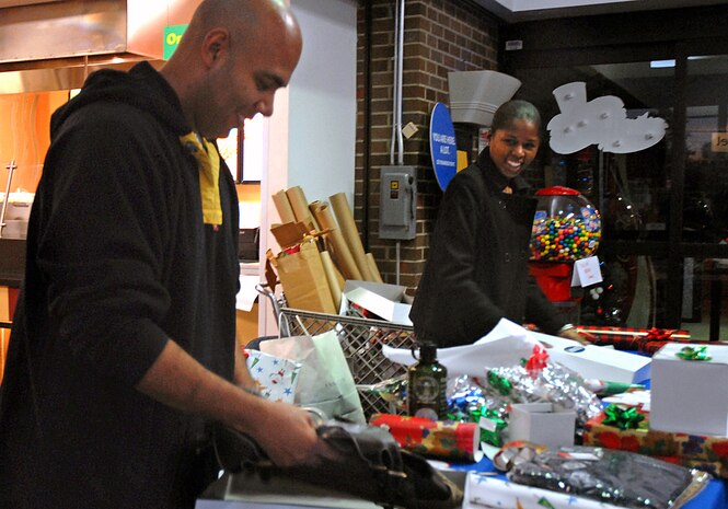 Tech. Sgt. Elliot Reed, 437th Airlift Wing Safety Office and Staff Sgt. Stephanie Scott, 437 AW Legal Office, volunteered at the Charleston AFB Exchange to wrap presents for BX patrons Monday. Both volunteered to wrap presents to raise money for the Airlift Wing Booster Club. (U.S. Air Force photo/Tech. Sgt. Paul Kilgallon)