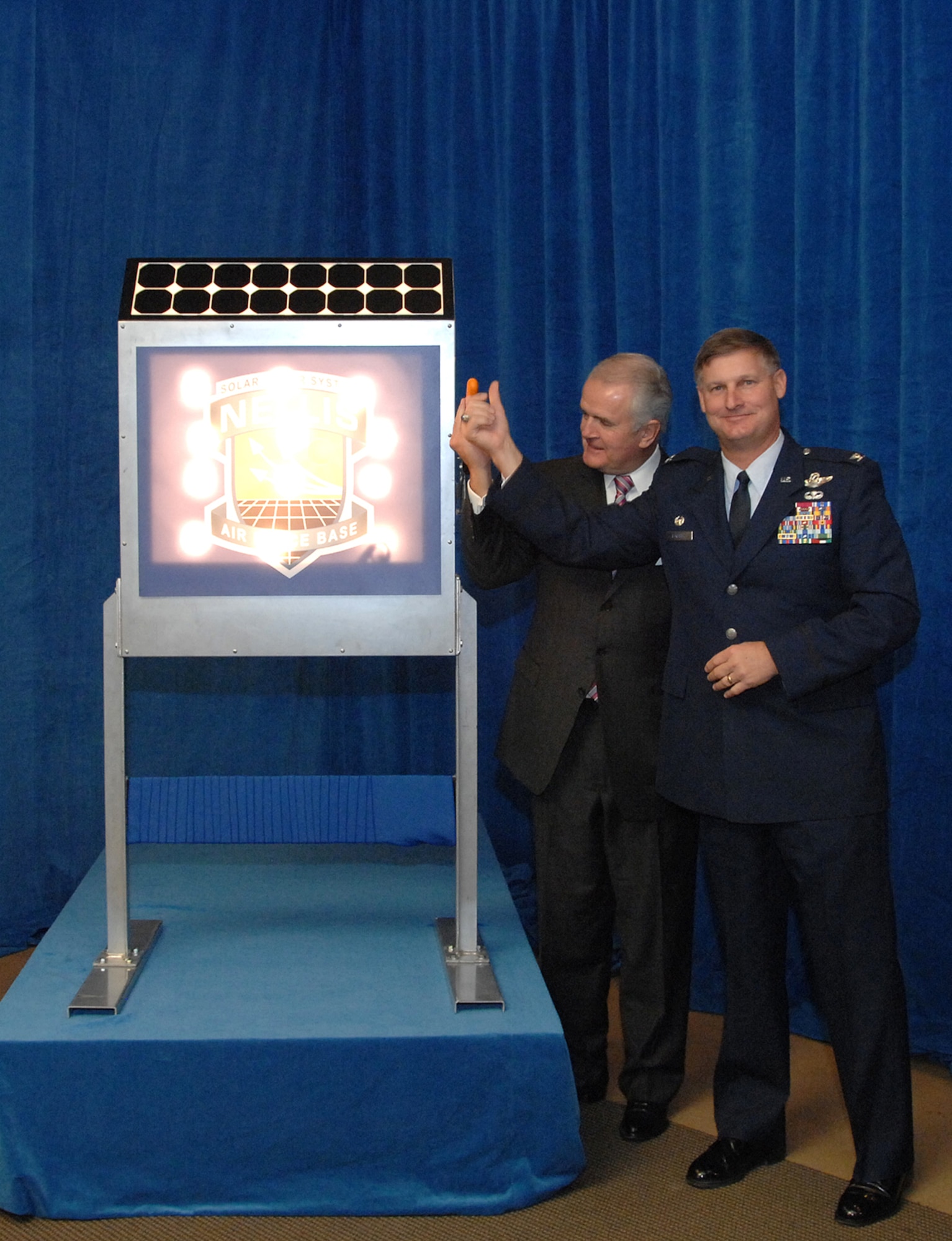 Col. Michael Bartley, 99th Air Base Wing commander, Nellis AFB, along with Nevada Governor Jim Gibbons flip the switch to the North America's largest solar photovoltaic power plant located at Nellis Air Force Base, Nev., Dec. 17, 2007. The Solar Power System is a $100 million project, covering a total of 140 acres and providing over 14.2 megawatts of electricity. The Nellis Solar Power System will meet an average of 25 percent of Nellis' electricity requirements saving over $1 million dollars annually.
(U.S. Air Force photo by Staff Sgt. Scottie McCord)