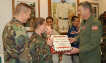 MINOT AIR FORCE BASE, N.D. -- Col. Marty Whelan, 91st Space Wing commader, presents Tech. Sgt. Tessa Brevik, 91st Maintenance Operations Squadron with a box of candy that would bring back memories from the 70s during a recent "hallway Christmas party" at the 91st SW headquarters building. (courtesy photo)