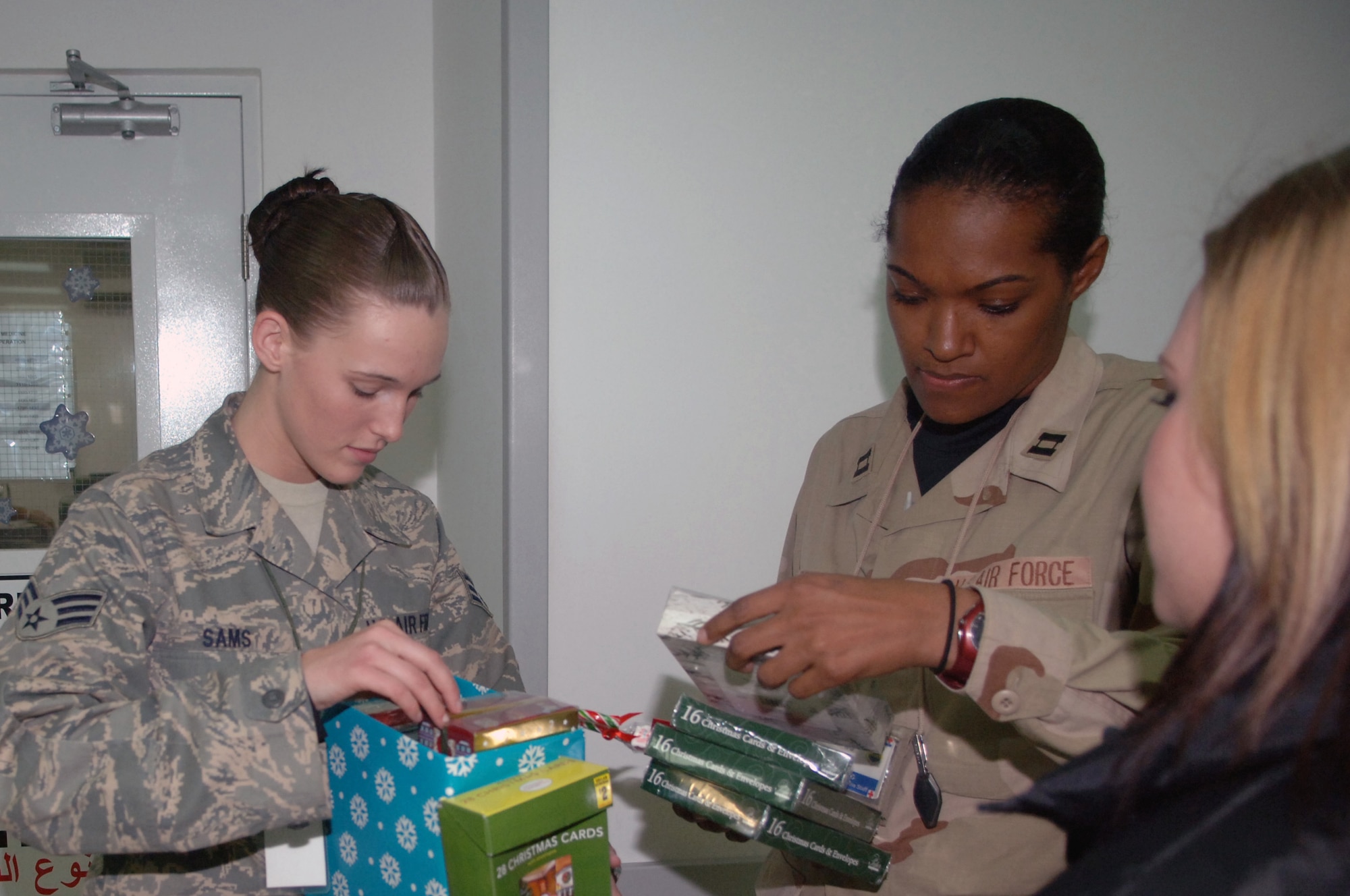 Senior Airman Amber Sams (second from left) helps Capt. Saunya Bright (second from right) find the perfect holiday card Nov. 30 at Balad Air Base, Iraq. As part of the self-initiated Cards for Troops program, Airman Sams handed out more than 30 boxes of holiday cards to Air Force Theater Hospital staff and patients here. Airman Sams is a 332nd Expeditionary Services Squadron recreation coordinator deployed from Langley Air Force Base, Va., and Captain Bright is assigned to the 332nd Expeditionary Medical Support Squadron and deployed from Lackland AFB, Texas. (U.S. Air Force photo/Senior Airman Terri Barriere) 
