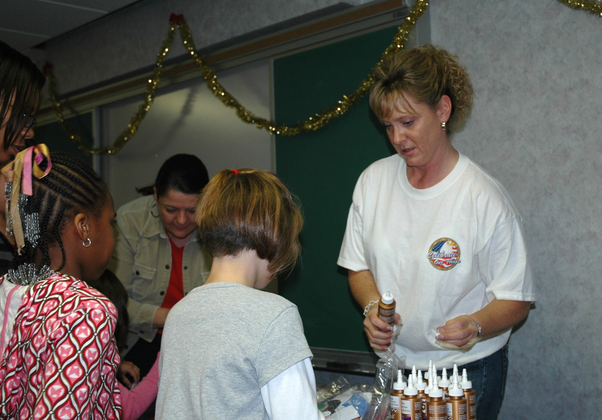 Master Sgt. Kat Mygan, 325th Mission Support Squadron family readiness manager, assists children with holiday crafting at the "Hearts Apart" holiday party here Dec. 13.  Sergeant Mygan cooridinated the party for  the more than 45 people in attendance.  (U.S. Air Force photo/Staff Sgt. Timothy R. Capling)