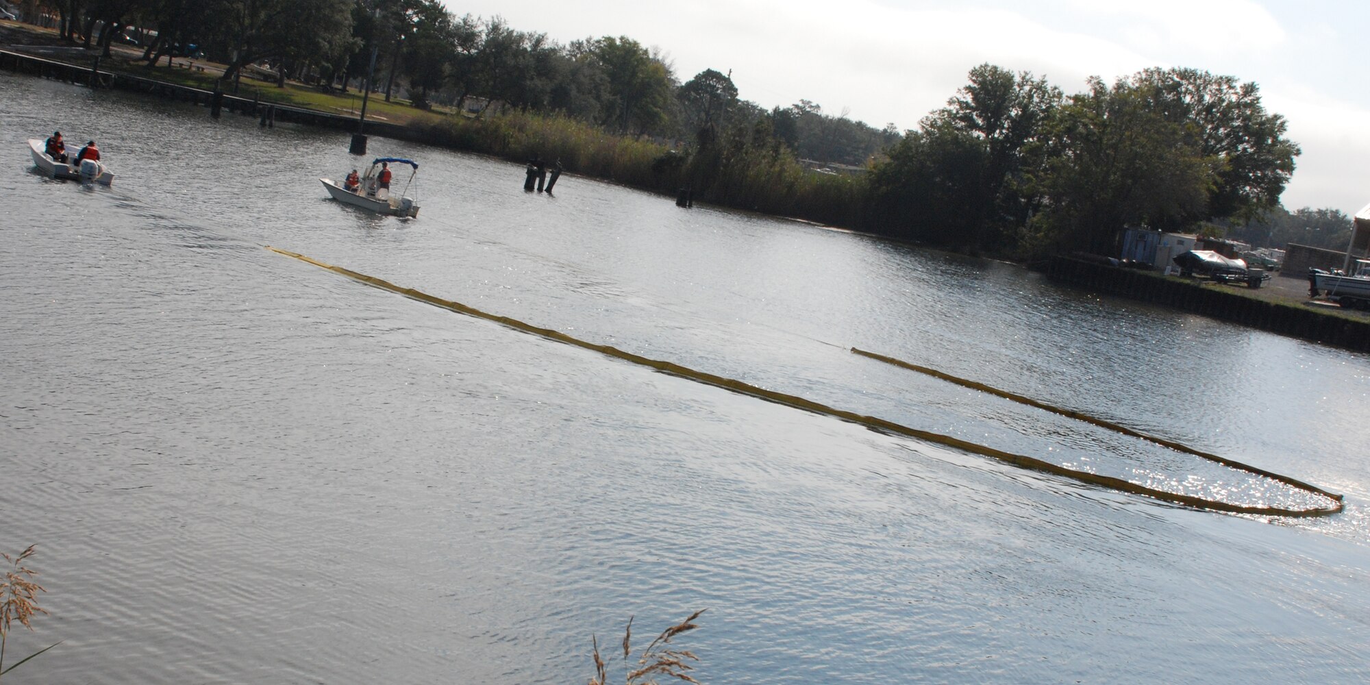 EGLIN AIR FORCE BASE, Fla. -- U.S. Coast Guardsmen employed the use of a 150-foot catenary tow, a boom pulled at the ends by boats to collect remnants of fuel floating on the surface of the water, during a fuel spill exercise Dec. 14 at Weekly Bayou. The Air Force and Coast Guard deployed more than 6,500 feet of boom during a week-long training exercise familiarizing them with the processes and equipment needed to clean up fuel spilled into the waters bordering Eglin's southern edge. Eglin has a water front bulk fuel storage facility that receives a barge of more than one million gallons of jet fuel every eight to 10 days. (U.S. Air Force photo by Staff Sgt. Mike Meares)