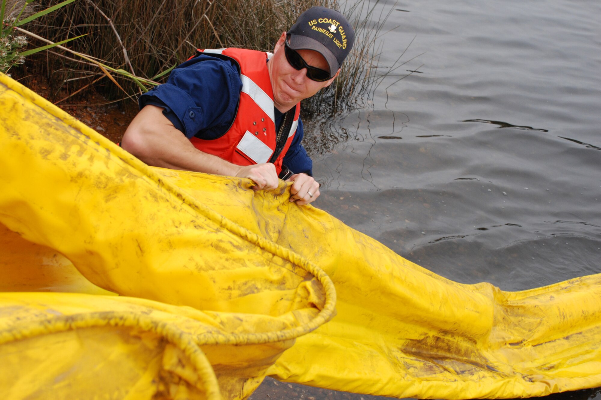 EGLIN AIR FORCE BASE, Fla. -- U.S. Coast Guard Boatswain Mate 2nd Class Jesse Duane, Barnegat Light, N.J., pulls boom out of a trailer as a boat drags it into the water Dec. 14 to be deployed into Weekly Bayou during a fuel spill exercise. The Air Force and Coast Guard deployed more than 6,500 feet of boom during a week-long training exercise familiarizing them with the processes and equipment needed to clean up fuel spilled into the waters bordering Eglin's southern edge. Eglin has a water front bulk fuel storage facility that receives a barge of more than one million gallons of jet fuel every eight to 10 days. (U.S. Air Force photo by Staff Sgt. Mike Meares)