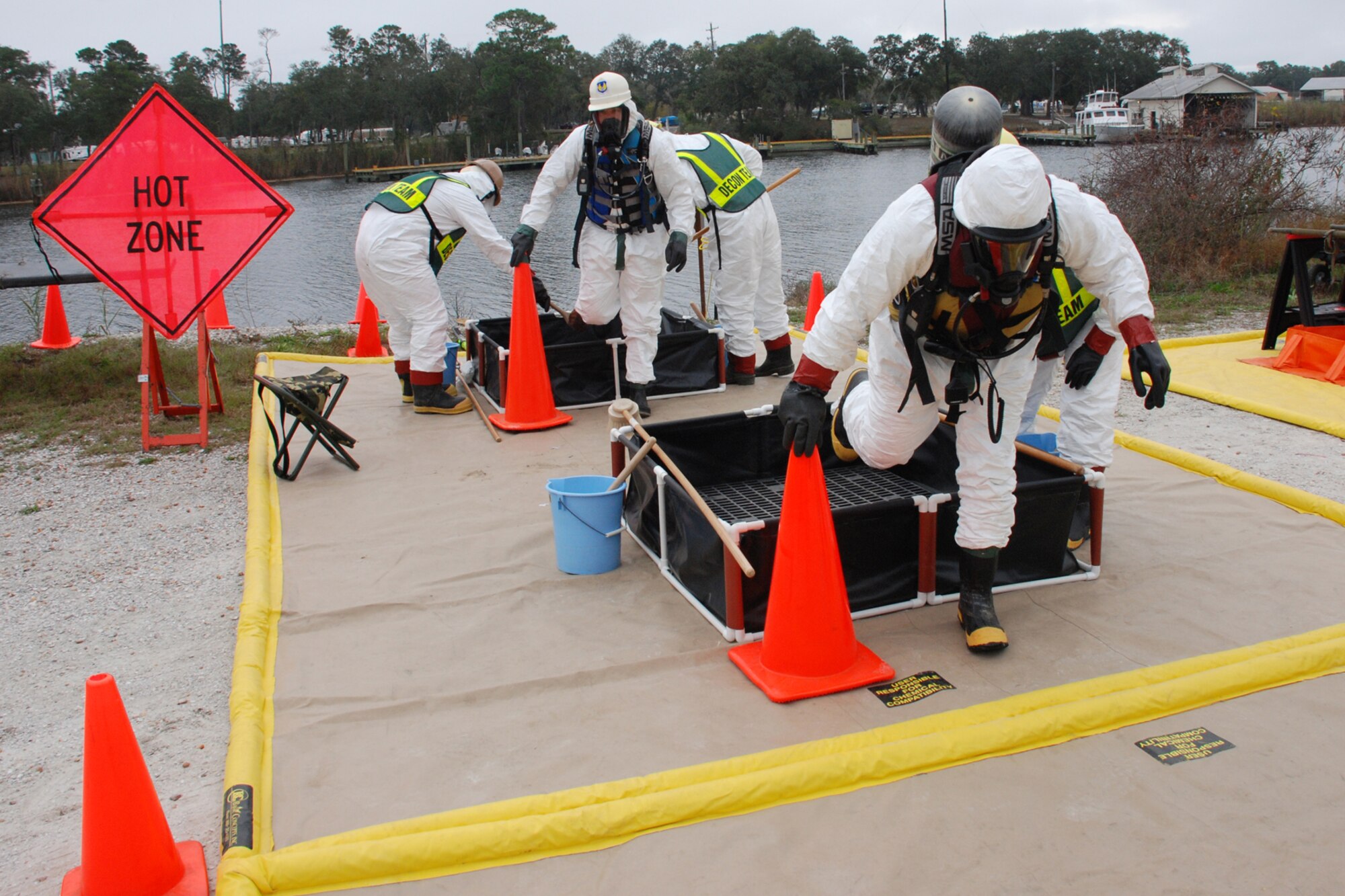 EGLIN AIR FORCE BASE, Fla. -- After returning from the a row boat trip into contaminated waters of Weekly Bayou, two Coast Guardsmen get washed down at the decontamination site during a fuel spill exercise Dec. 14. The Air Force and Coast Guard deployed more than 6,500 feet of boom during a week-long training exercise familiarizing them with the processes and equipment needed to clean up fuel spilled into the waters bordering Eglin?s southern edge. Eglin has a water front bulk fuel storage facility that receives a barge of more than one million gallons of jet fuel every eight to 10 days. (U.S. Air Force photo by Staff Sgt. Mike Meares)