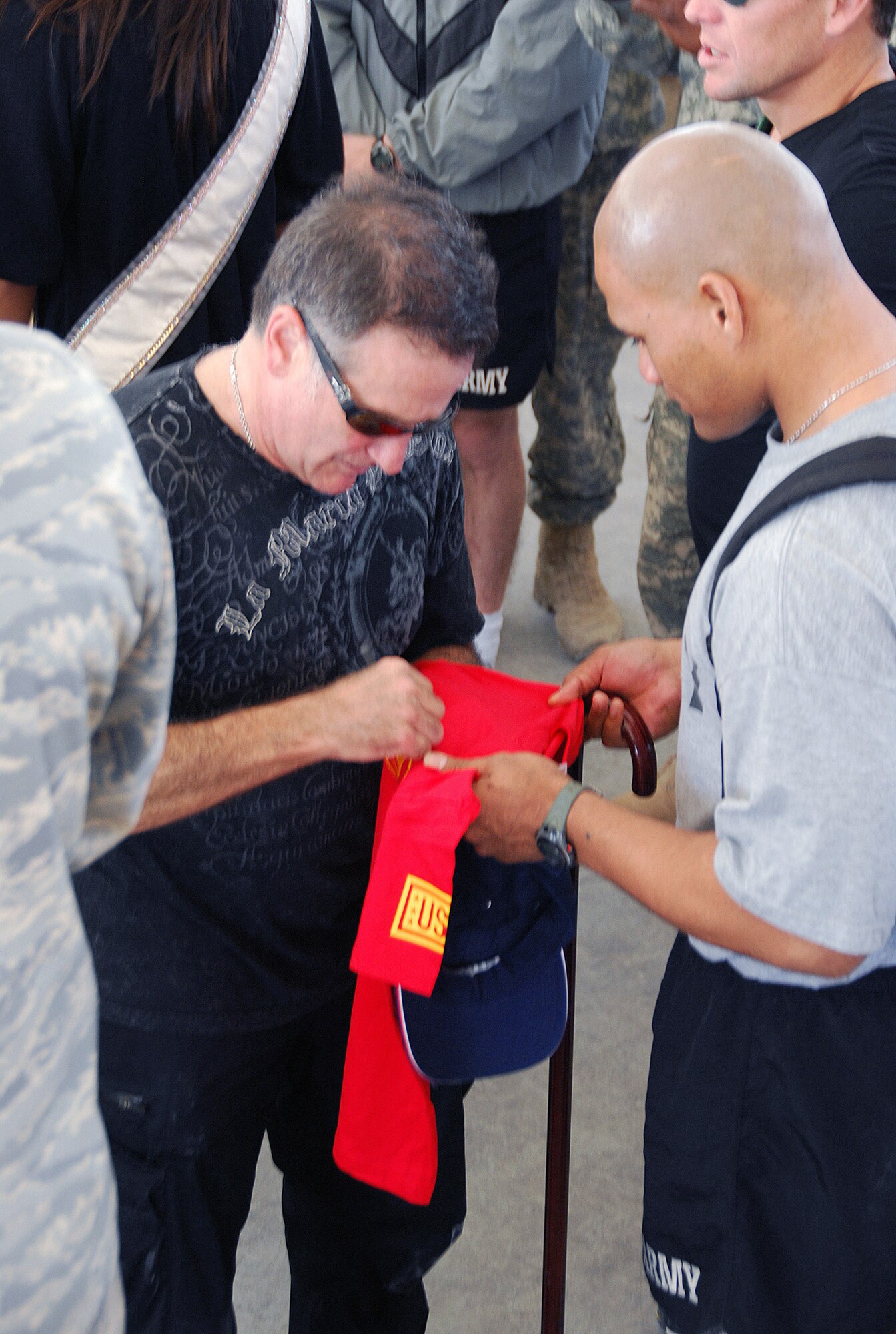 Robin Williams signs a T-shirt for Army Sgt. Semeli Toilolo during a Dec. 17 appearance at a Southwest Asia air base. Sergeant Toilolo is recovering from wounds he received in a suicide bomber attack. Mr. Williams is touring with the United Service Organizations as part of the 2007 holiday tour throughout Southwest Asia. Other celebrities on the tour included Rachel Smith, Miss USA, Kid Rock, Lewis Black and Lance Armstrong. (U. S. Air Force photo/Staff Sgt. Douglas Olsen) 
