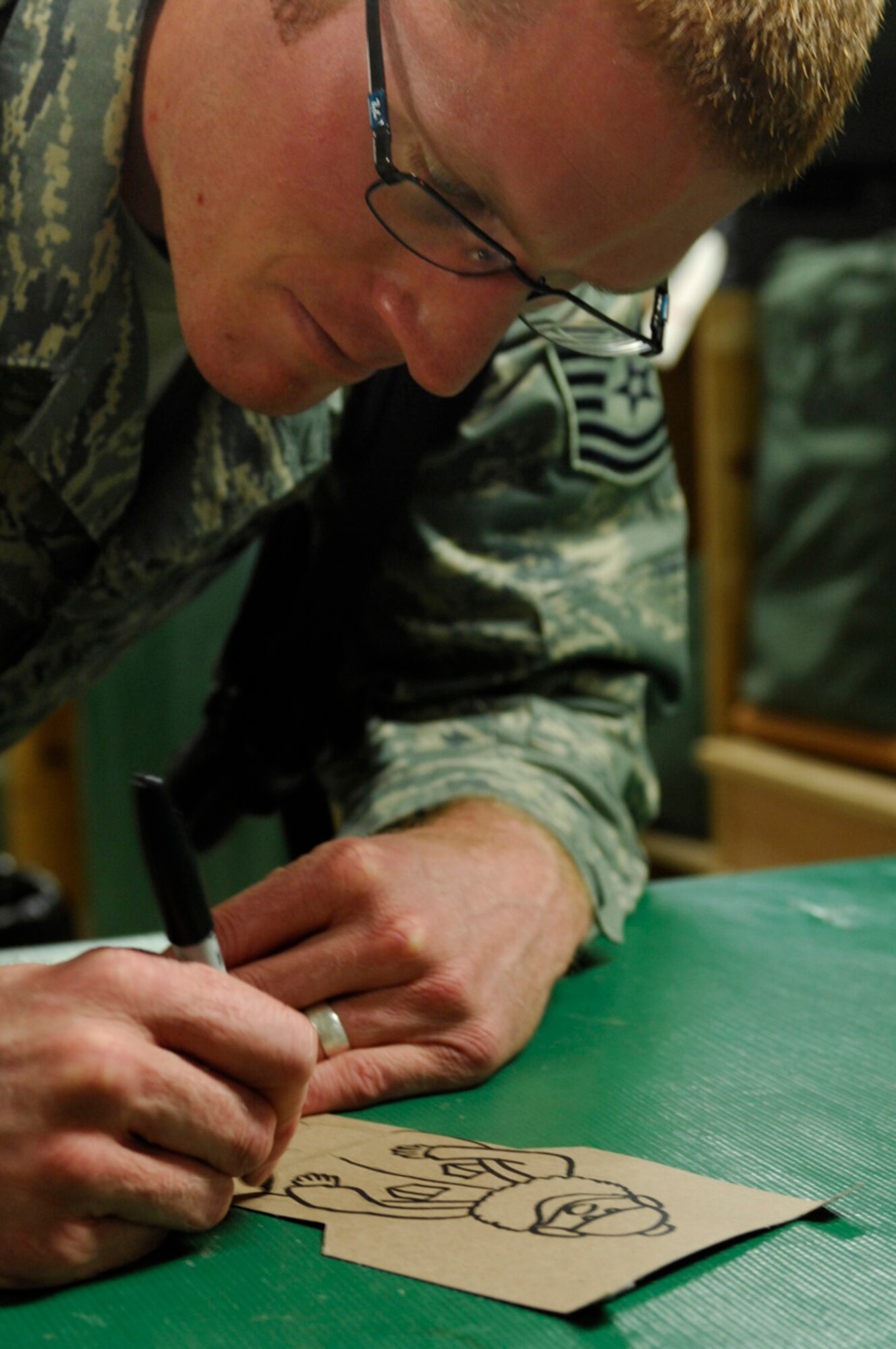 BAGRAM AIR BASE, Afghanistan - Tech. Sgt. Ryan McMaster, an aircrew life support technician with the 774th Expeditionary Airlift Squadron here, draws cartoon characters for a holiday diorama he created from locally-procured materials, Dec. 14, 2007.  (U.S. Air Force photo/Staff Sgt. Joshua T Jasper)

