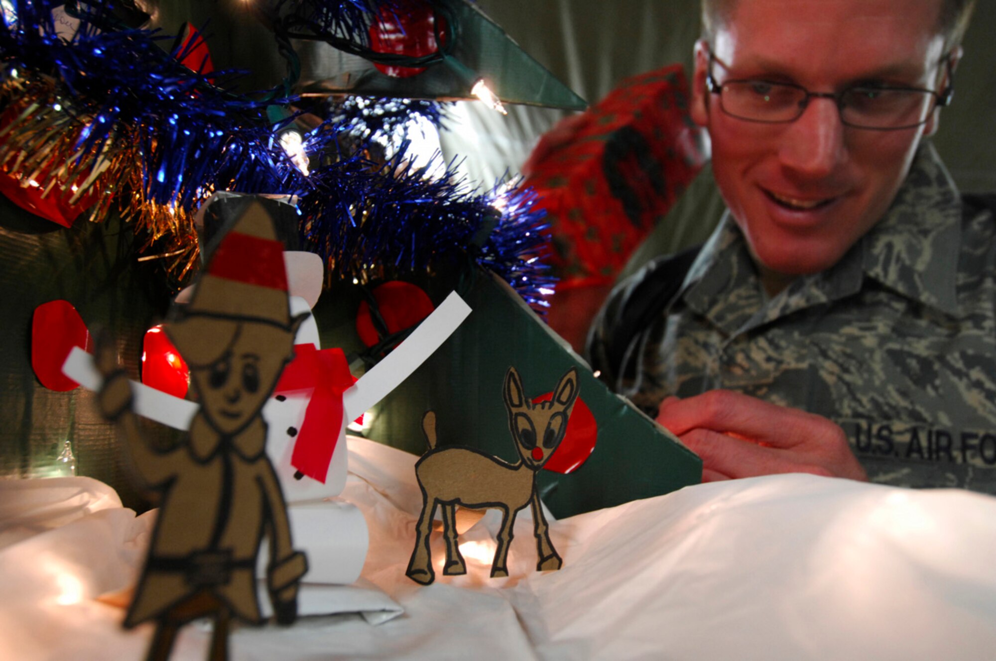 BAGRAM AIR BASE, Afghanistan - Cartoon characters in a holiday diorama created by Tech. Sgt. Ryan McMaster, an aircrew life support technician with the 774th Expeditionary Airlift Squadron, stand by as he shakes a gift under a tree.  Both the tree and the diorama were made from locally-procured materials, Dec. 14, 2007.
(U.S. Air Force photo/Staff Sgt. Joshua T Jasper)