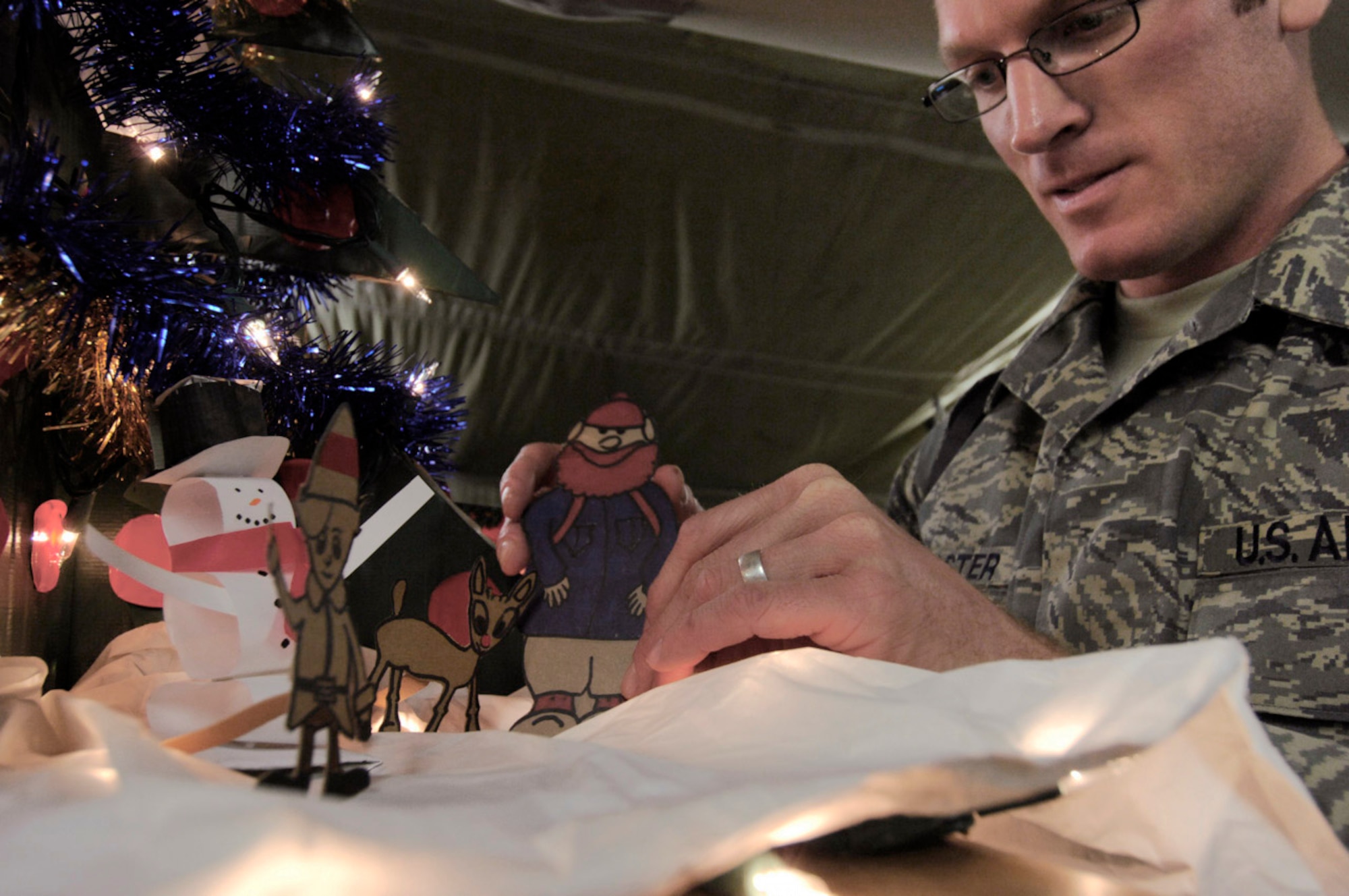 Tech. Sgt. Ryan McMaster places cartoon characters in a holiday diorama next to a tree Dec. 14 at Bagram Air Base, Afghanistan. He created both from locally-procured materials. Sergeant McMaster is an aircrew life support technician with the 774th Expeditionary Airlift Squadron. (U.S. Air Force photo/Staff Sgt. Joshua T. Jasper) 