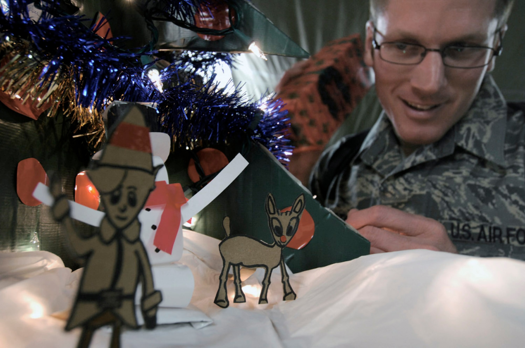 Tech. Sgt. Ryan McMaster looks at cartoon characters he created in a holiday diorama made from locally-procured materials Dec. 14 at Bagram Air Base, Afghanistan. Sergeant McMaster is an aircrew life support technician with the 774th Expeditionary Airlift Squadron. (U.S. Air Force photo/Staff Sgt. Joshua T. Jasper)(