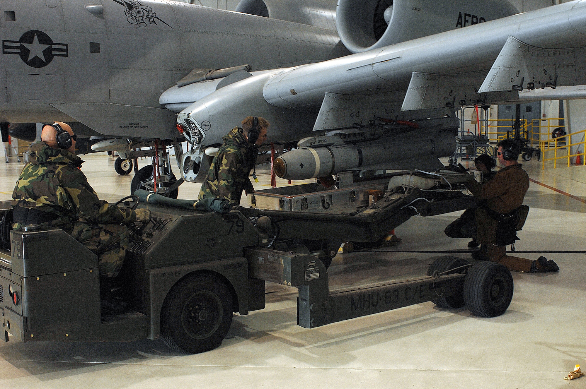 WHITEMAN AIR FORCE BASE, Mo. -- Tech. Sgt. Ken Portell, 442nd Aircraft Maintenance Squadron, drives the jammer into place under the inert TGM 65 Maverick missile on a A-10 weapons pylon station Dec. 19. Master Sgt. Jim Kirksey, Airman 1st Class Shane Dunn, and Senior Airman Nathan Kern, 442d AMXS, verify the bracket is lined up with the missile before the jammer arm is lifted to make contact. The AGM-65 Maverick is a tactical air-to-surface missile designed to strike a wide range of surface fixed or moving targets. Maverick can be released from safe range minimizing exposure to the enemy's air defenses. (U.S. Air Force photo/Tech. Sgt. Samuel A. Park) 