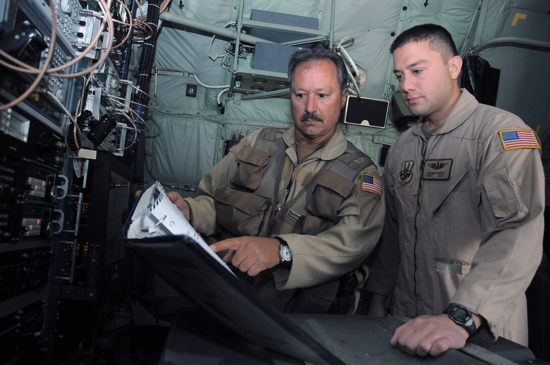 Senior Master Sgt. Michael Kovach (left) and his son, Master Sgt. Shawn Kovach, look through an EC-130J Commando Solo technical order manual while going over updated emergency procedures Nov. 26 in Southwest Asia. Both Airmen are assigned to the 43rd Expeditionary Electronic Combat Squadron and are deployed from the Pennsylvania Air National Guard's 193rd Special Operations Wing from Middletown, Penn. (U.S. Air Force photo/Staff Sgt. Tia Schroeder) 
