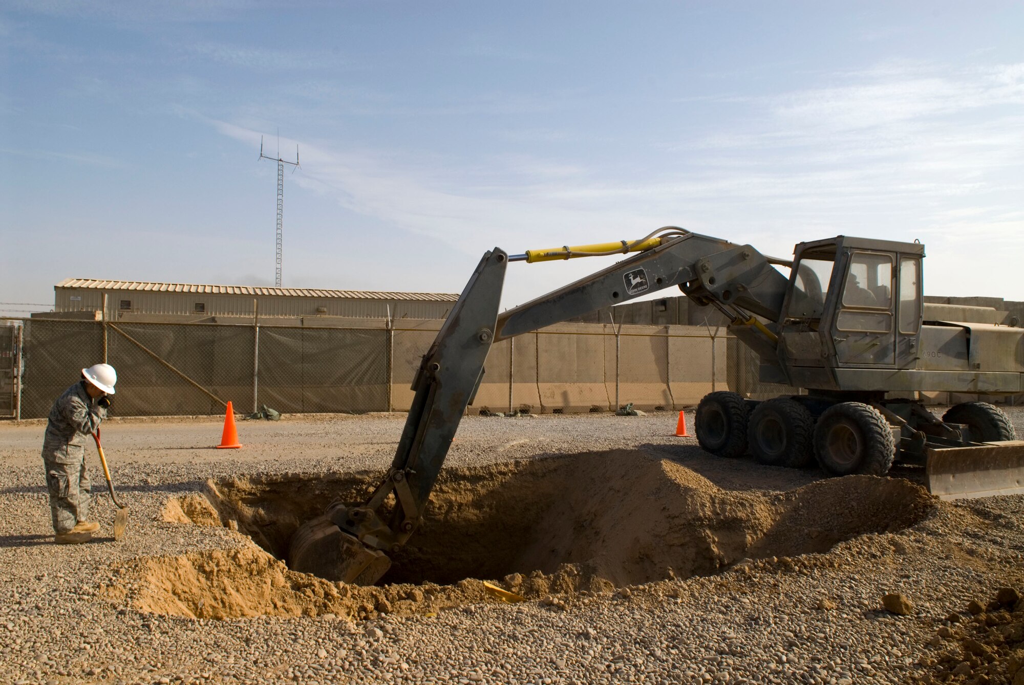 BALAD AIR BASE, Iraq -- Senior Airman Kristine Johnson, a 332nd Expeditionary Civil Engineer Squadron utilities technician, guides Staff Sgt. William Huff, a heavy equipment operator from the 332nd ECES, as he digs for a sewer line here, Dec. 18. Members from different shops such as Utilities and Heavy Equipment work alongside one another to ensure that tasks are complete. Airman Johnson is deployed from Yokota Air Base, Japan and Sergeant Huff is deployed from Spangdahlem AB, Germany. (U.S. Air Force photo/Staff Sgt. Joshua Garcia)