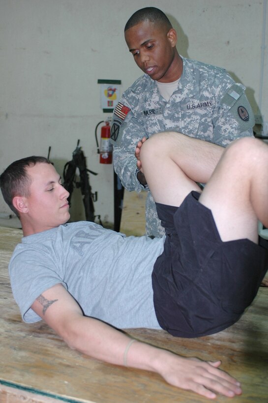 Army Staff Sgt. David Marr, Headquarters and Headquarters Company, Task Force Phantom, shows Army Pfc. Jonathan Lipinski, chemical operations specialist, 355th Chemical Company, how to keep perform an abdominal exercise at Camp Victory, Iraq. In addition to being a master driver, Marr, an Ithaca, N.Y., native, is a licensed personal trainer and has been helping others achieve a healthy lifestyle since 2001. Photo by Sgt. Laura M. Bigenho, USA