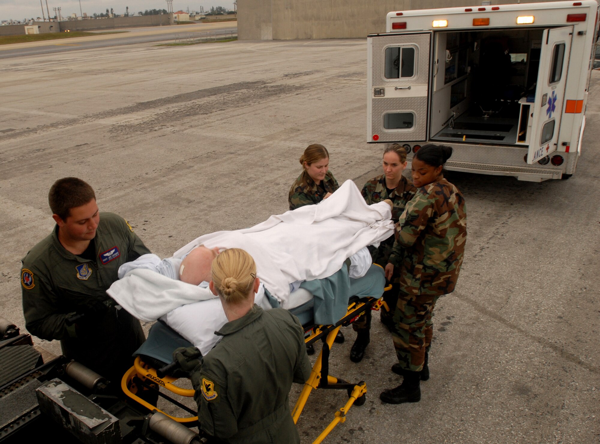 Airmen from the 18th Aeromedical Evacuation Squadron, the 18th Medical Operations Squadron and 18th Aerospace Medicine Squadron, work together to carry a patient from Yokota Air Base, Japan, onto a KC-135 Stratotanker bound for Kadena Air Base, Japan, Dec. 18. The patient will stay at the Camp Lester Naval Hospital for the night to receive critical care before being transported to Travis Air Force Base, Calif., for further treatment. The 18th AES travels throughout the Pacific picking up critical patients and transporting them to hospitals that can meet their needs. (U.S. Air Force photo/Staff Sgt. Chrissy FitzGerald)