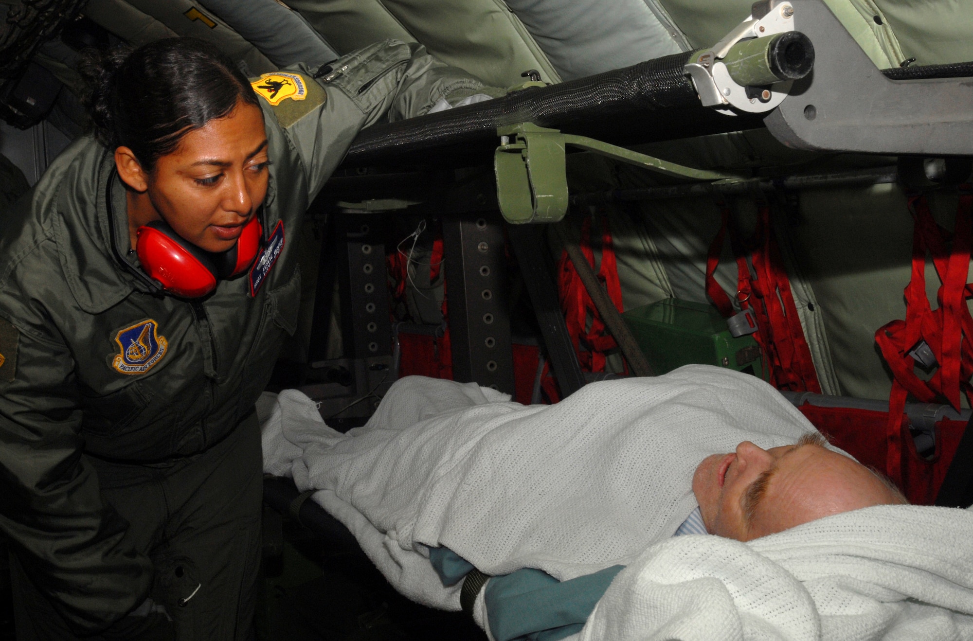 Staff Sgt Leslie Green, medical technician from the 18th Aeromedical Evacuation Squadron, checks with the patient to make sure he is alright during the flight back to Kadena Air Base, Japan, Dec. 18. The 18th AES travels throughout the Pacific picking up critical patients and transporting them to hospitals that can meet their needs. (U.S. Air Force photo/Staff Sgt. Chrissy FitzGerald)