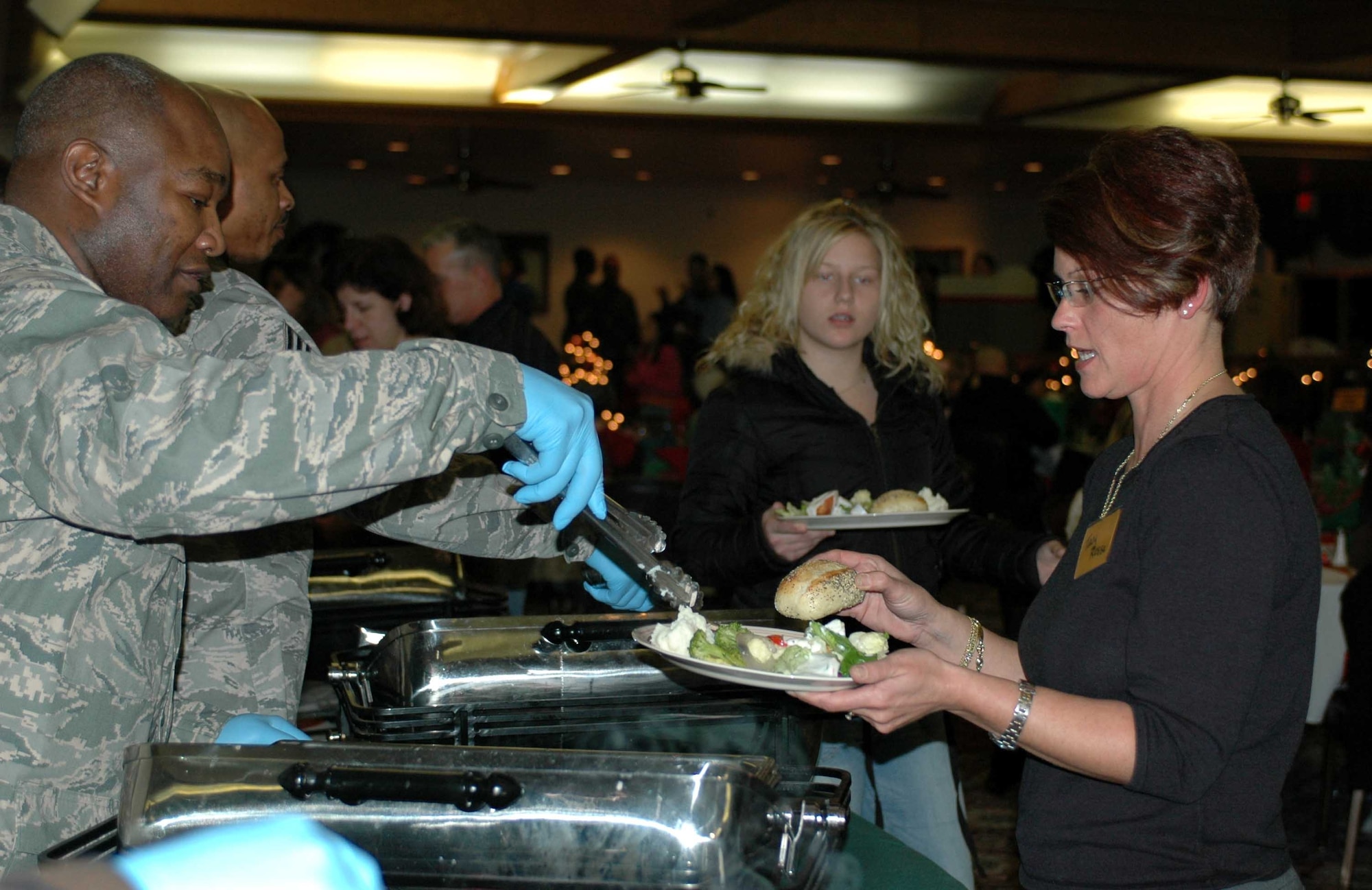 Base leadership serve dinner to attendees of the Deployed Spouses Dinner Dec. 18 at the Travis Conference Center. Spouses learn about base and local resources available to them while socializing with other families in a social setting. (U.S. Air Force photo/Senior Airman Shaun Emery)