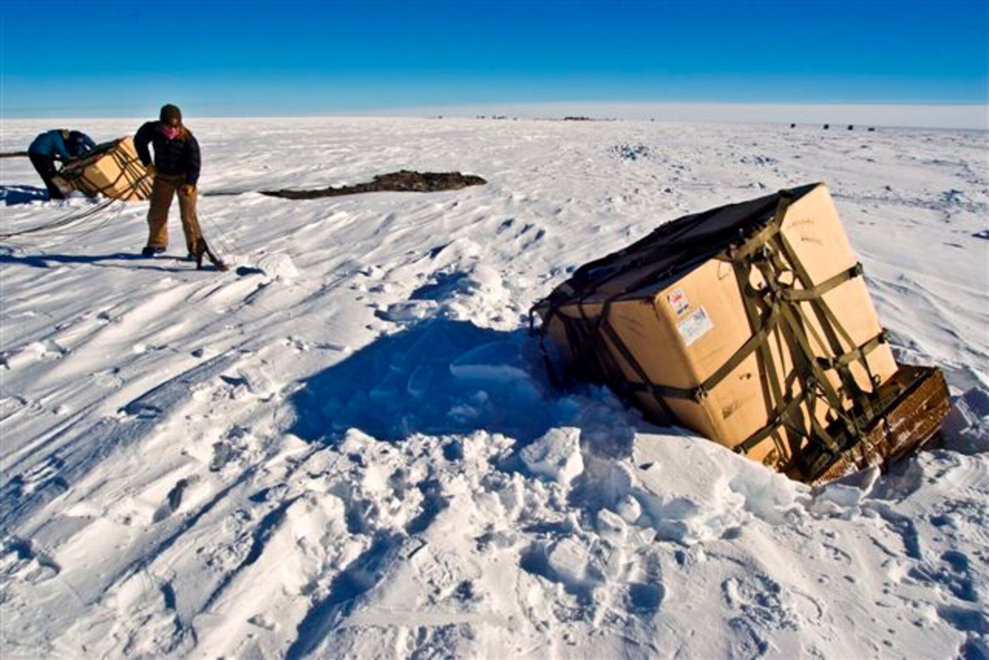 Containerized Delivery System bundles are recovered by a ground crew member at the South Pole. The bundles were airdropped by a McChord C-17 supporting Operation Deep Freeze.  The 13th Air Force-led Operation Deep Freeze is a unique joint and total force mission that has supported the National Science Foundation and U.S. Antarctic Program since 1955.  By validating the C-17 capability to complete airdrop missions at the Geographical South Pole, Joint Task Force-Support Forces Antarctica demonstrated its ability to provide mid-winter emergency re-supply and flexible support to the National Science Foundation and U.S. Antarctica Program. (Courtesy Photo by B.K. Grant)
