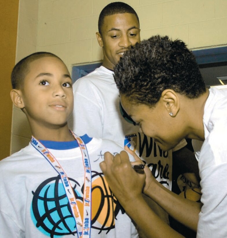 Alana Beard autographs the T-shirt of Shawn Robinson, 9, as his father, Staff Sgt. Daniel Robinson observes. Sergeant Robinson is assigned to the 316th Civil Engineer Squadron as a fire prevention technician.(US Air Force/Bobby Jones)