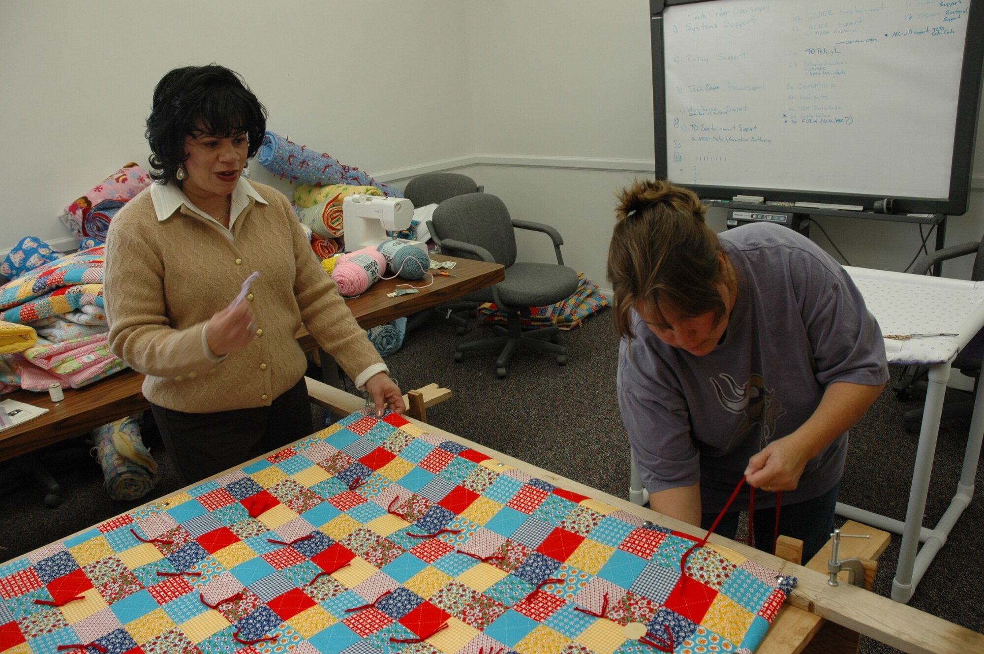 Terry McCurdy and Alesia Harrah finalize a quilt for the 510th Combat Sustainment Squadron Christmas Charity project (from left to right). Employees of the squadron donated fabric, batting, yarn and finances for the event. Four charities have been chosen to receive the donations; a shelter for women and children, a 24-hour crisis day care, a parent and teen youth program and the Airman & Family Readiness Center here at Hill Air Force Base.