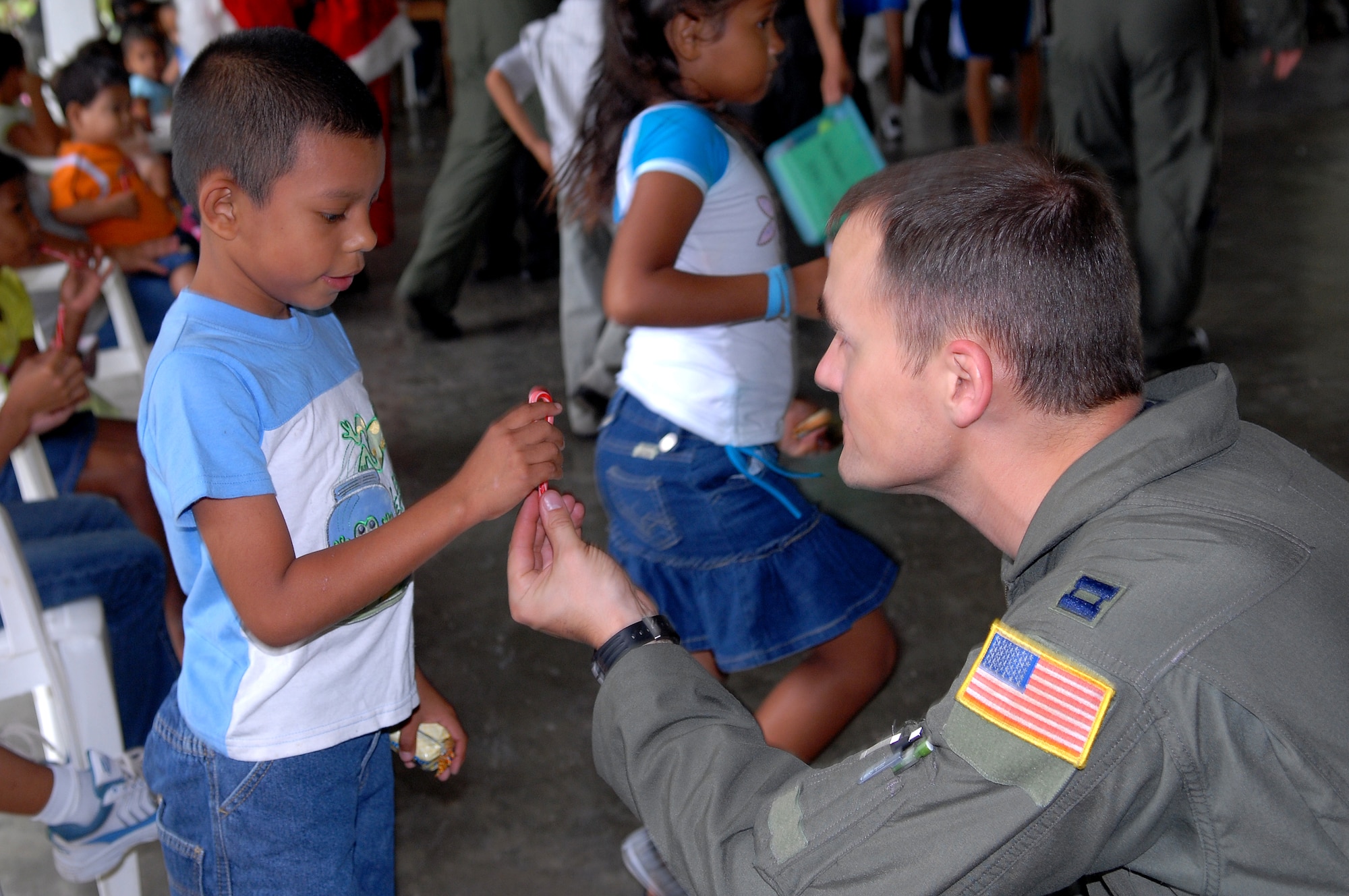 Capt. Patrick Dube, an aircraft commander with the 9th Special Operations Squadron, hands a Honduran orphan a candycane at Aldea Infantil S.O.S Orphanage in La Ceiba, Honduras during Operation Christmas Wish Dec. 13. Captain Dube was part of a 16 person team that helped deliver more than 875 Christmas packages to five different Honduran orphanages. (U.S. Air Force photo/Senior Airman Ali Flisek)
