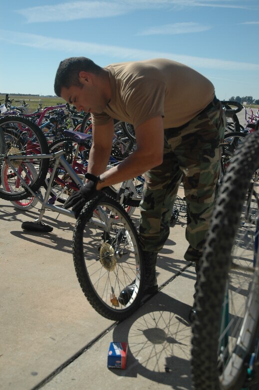 Staff Sgt. Rene Garza of the 45th Civil Engineer Squadron pulls a tire from a wheel hub as he fixes bicycles for the Patrick Fire Department's Bike Program. The program donates used bikes to local charities for distribution to needy individuals. (U.S. Air Force photo by Airman David Dobrydney)