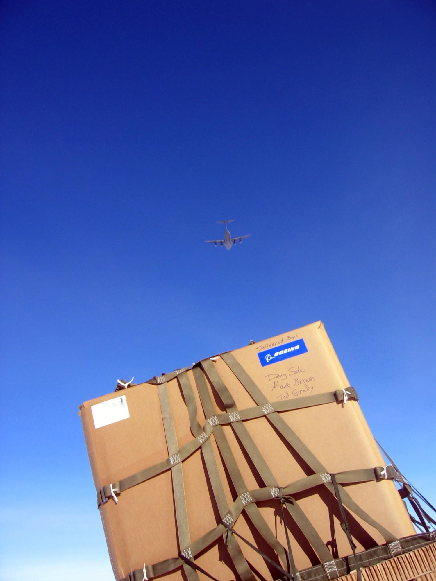 A C-17 flys above a Containerized Delivery System bundle is airdropped to the South Pole. By validating the C-17 capability to complete airdrop missions at the Geographical South Pole, JTF-SFA demonstrated its ability to provide mid-winter emergency re-supply and flexible support to the National Science Foundation and U.S. Antarctica Program. (U.S. Air Force photo)

