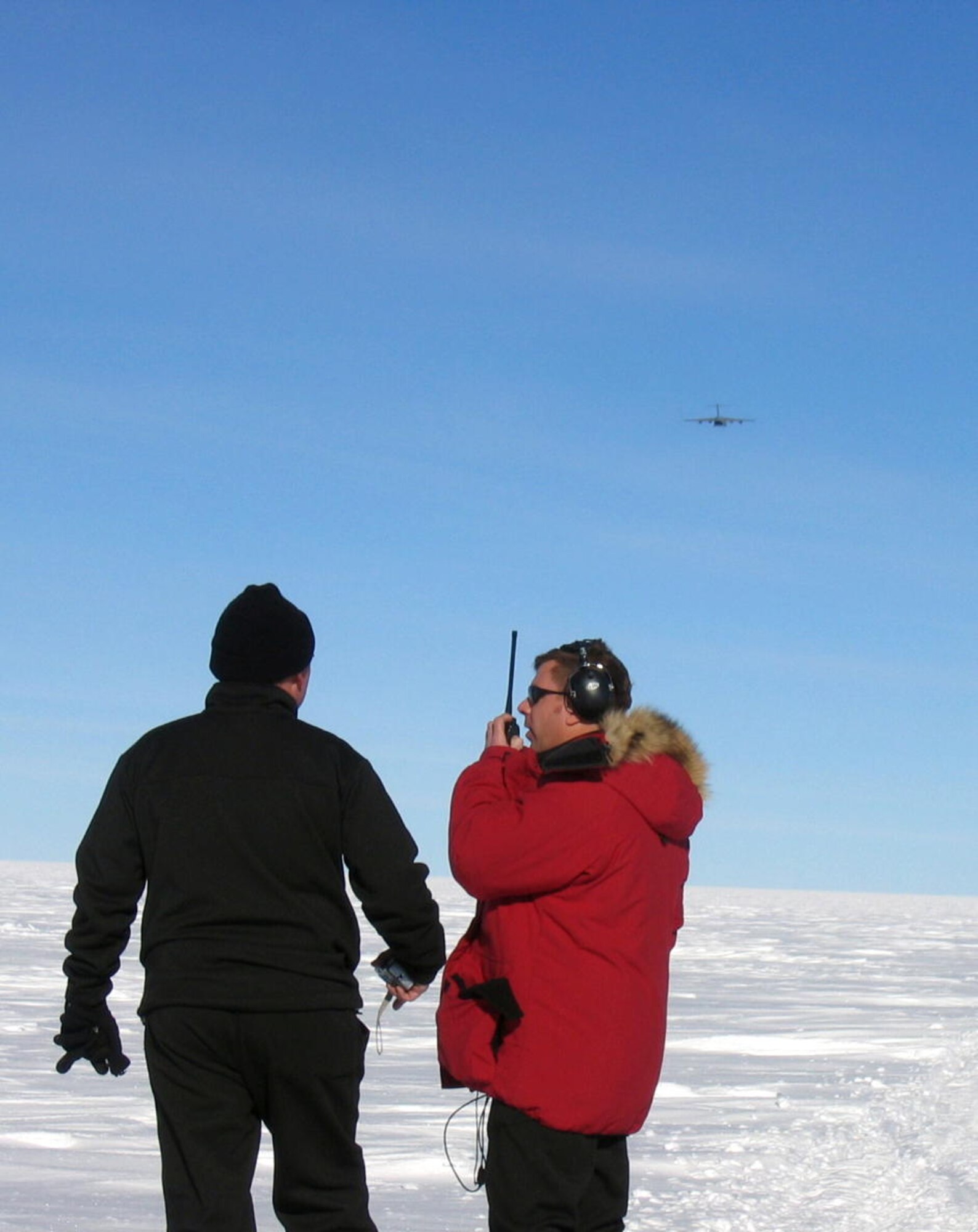 A drop zone controller guides the C-17 aircrew members during the Containerized Delivery System airdrop of supplies to the South Pole. By validating the C-17 capability to complete airdrop missions at the Geographical South Pole, JTF-SFA demonstrated its ability to provide mid-winter emergency re-supply and flexible support to the National Science Foundation and U.S. Antarctica Program.   (U.S. Air Force photo)