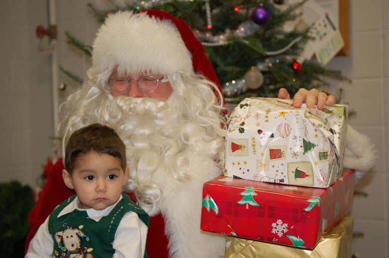 Master Sergeant Todd  "Santa" Condel is normally a 'blue suiter' with the Air Force Reserve serving as the Non-commissioned officer in charge of combat arms. During a recent party for the family members of deployed Alamo Wing security forces Airmen, Sergeant Condell traded Air Force blue for Santa Red to entertain children like 17-month-old Joseph Peche who's father is currently serving in Iraq. Joseph isn't sure exactly how to take the red suited sergeant. (U.S. Air Force Photo/Airman Viola Hernandez)