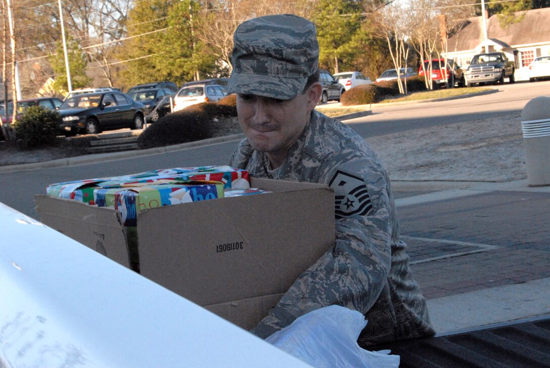 Master Sgt. Jerry Glover picks up a box of presents Dec. 18 to deliver to children in the local foster care system near Pope Air Force Base, N.C. Sergeant Glover is the 43rd Security Forces Squadron first sergeant. (U.S. Air Force photo/Airman Mindy Bloem)
