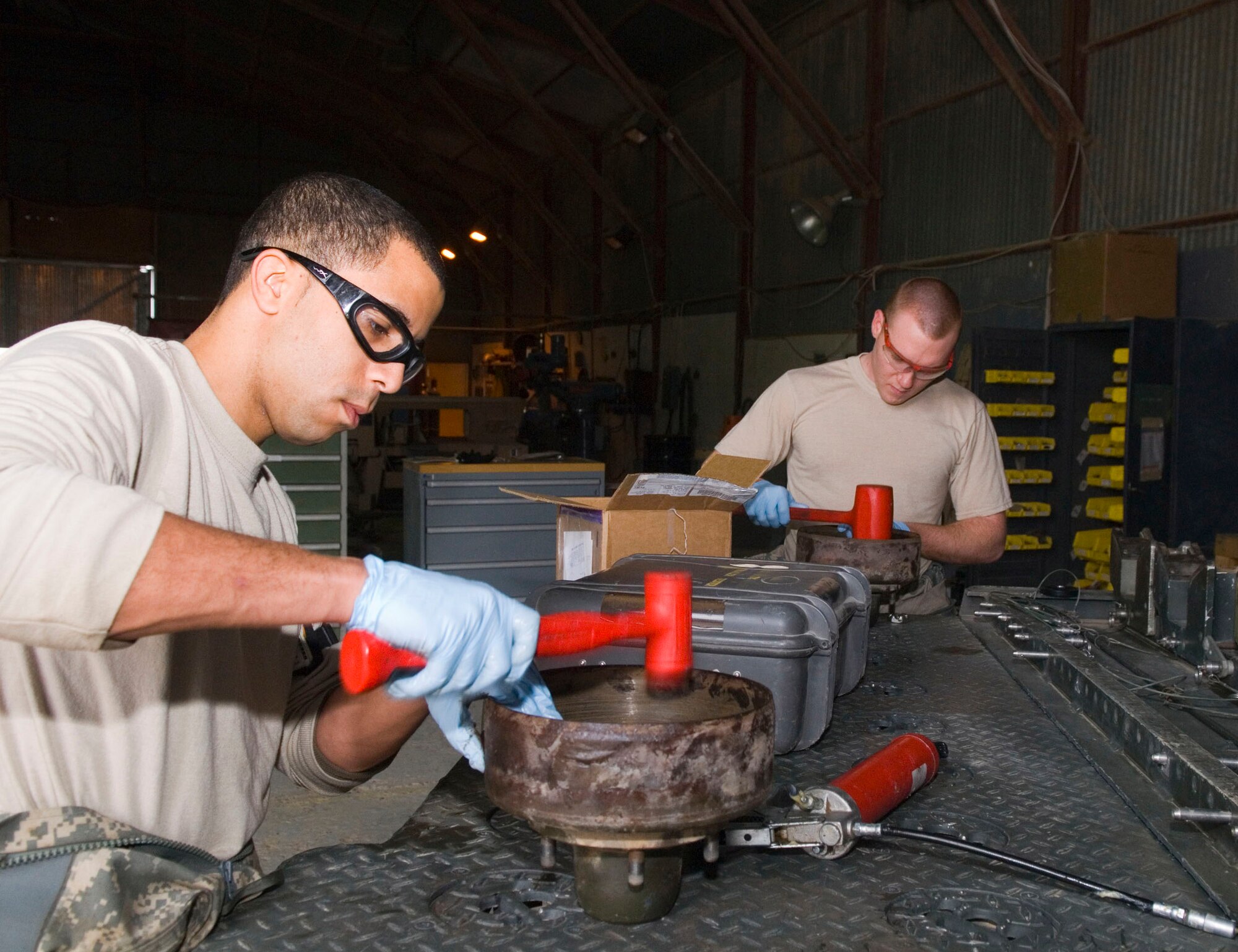 Staff Sgt. Elvin Rose and Airman 1st Class Justin Porter, both 332nd Expeditionary Maintenance Squadron munitions equipment maintainers, secure bearing seals onto the brake drums for a munitions trailer during a 720-day inspection here, Dec. 19. Munitions equipment undergoes several types of inspections depending on how long the item has been used. Sergeant Rose and Airman Porter are deployed from Spangdahlem Air Base, Germany (U.S. Air Force photo/Staff Sgt. Joshua Garcia)