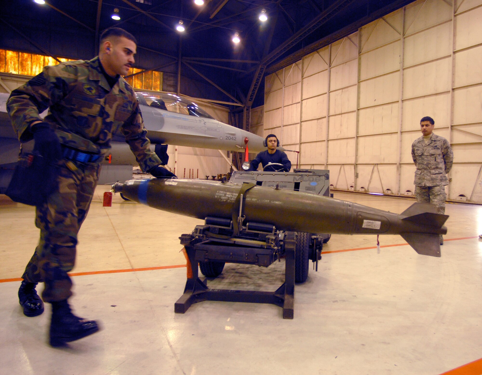 Staff Sgt. Danny Colon (foreground) and Airman 1st Class Jay Maldonado (back left) prepare to move a bomb into position during the weapons load competition as Senior Airman Erwin Viray judges Dec. 14 at Kunsan Air Base, South Korea. This was the final weapons load competition between the 80th and 35th Fighter squadrons for 2007. Sergeant Colon and Airman Maldonado are from the 8th Aircraft Maintenance Squadron. (U.S. Air Force photo/Senior Airman Steven R. Doty)
