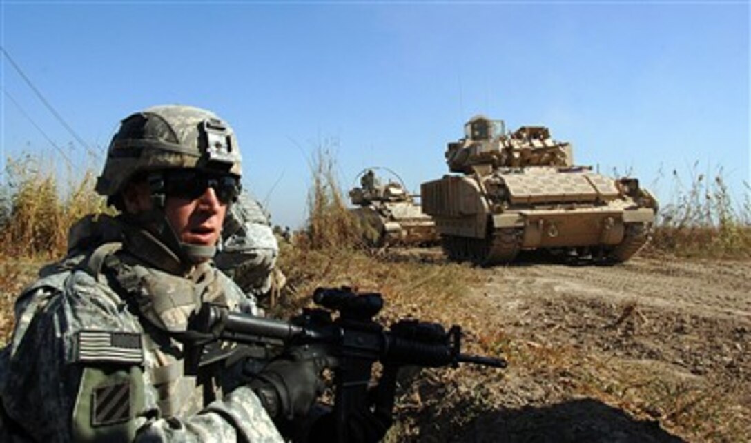 A U.S. Army soldier from 2nd Platoon, Bravo Company, 1st Battalion, 30th Infantry Regiment, 2nd Brigade Combat Team, 3rd Infantry Division maintains a security watch while M2A2 Bradley armored vehicles prepare to cross a bridge in Arab Jabour, Iraq, on Dec. 11, 2007.  