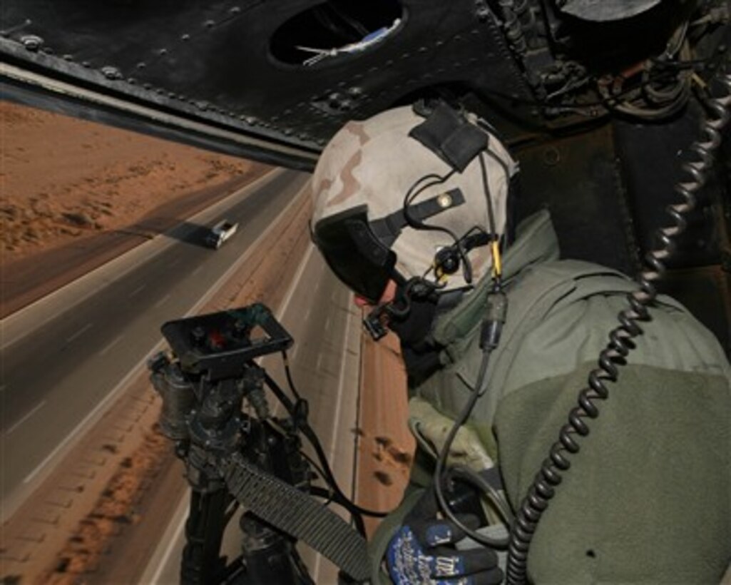 A U.S. Marine Corps UH-1N Huey helicopter crew chief scans to road below as his helicopter provides security for a coalition forces convoy in the Al Anbar province of Iraq, on Dec. 14, 2007.  The helicopter and crew are assigned to Marine Light/Attack Helicopter Squadron 773.  