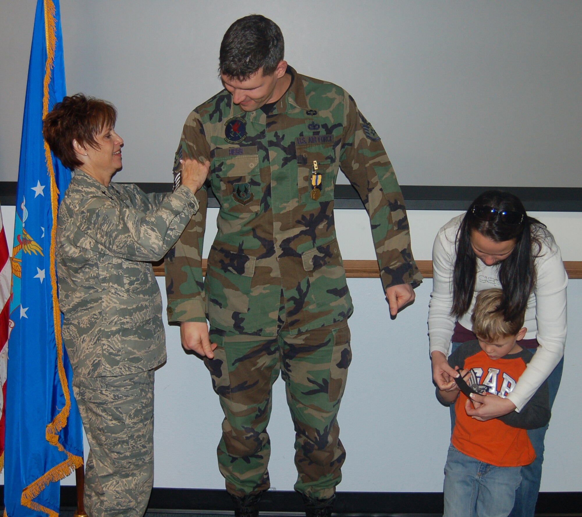 Tech. Sgt. Cory Hebb, 75th Security Forces Squadron, watches as Maj. Gen. Kathleen Close, Ogden Air Logistics Center commander, attaches his new rank during his STEP promotion ceremony Dec. 21. Sergeant Hebb’s wife, Tiffany, and 4-year-old son, Canyon, also ‘tacked’ a stripe on. (U.S. Air Force Photo by Senior Airman Brok McCarthy)