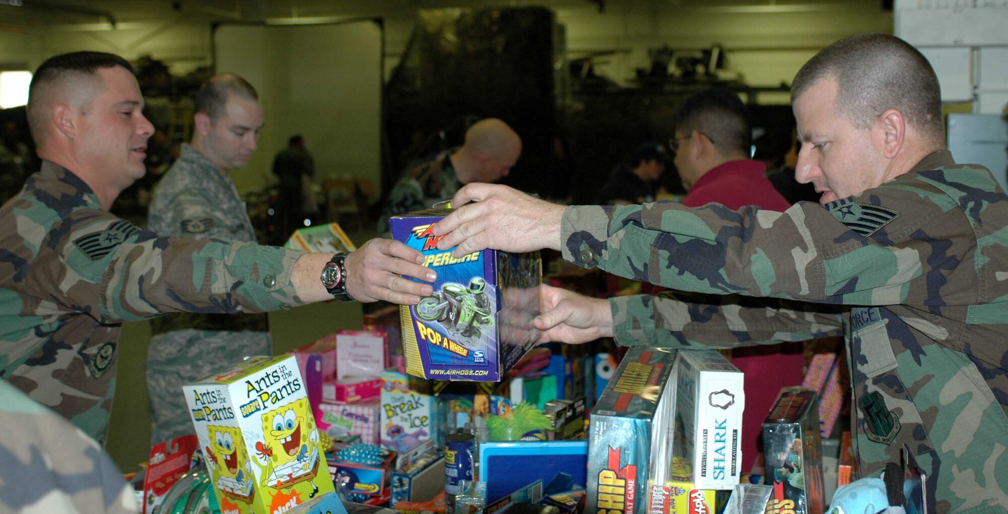 Tech. Sgt. Michael Brown, (right), 573rd Global Support Squadron, hands Tech. Sgt. Ian Hall, 573rd GSS, a toy during the Toys for Troops event held in Hangar P-1 Dec. 20. The event that gave Travis parents a chance to pick out some Christmas toys for their children. (U.S. Air Force photo/Staff Sgt. Matthew McGovern)