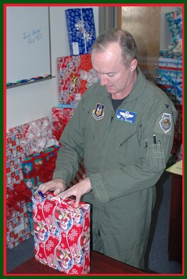 Col. Ed Walker, 917th Wing commander, wraps one of the gifts to be given to a needy child as part of Barksdale's Santas in Blues 2007 program Dec. 21 at the Bossier Civic Center. The 917th Wing donated $2,500 to the program this year. (U.S. Air Force photo/Master Sgt. Sherri Bohannon)