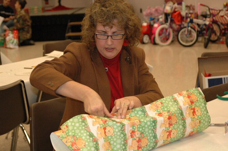 Donna McMillan, 917th Wing employee, wraps a gift to be given to a child at the Santas in Blues program.  (U.S. Air Force photo/Master Sgt. Sherri Bohannon)
