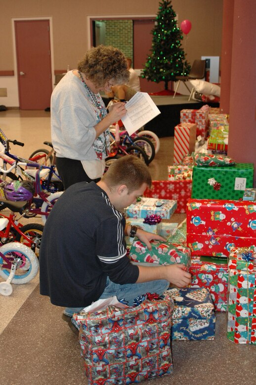 Taryn Montgomery, 917th Wing Santas in Blues chairperson, and Zach Bernard, spouse of 26th Operational Weather Squadron member, double-check gifts to make certain they match what is on the list.  (U.S. Air Force photo/Master Sgt. Sherri Bohannon)