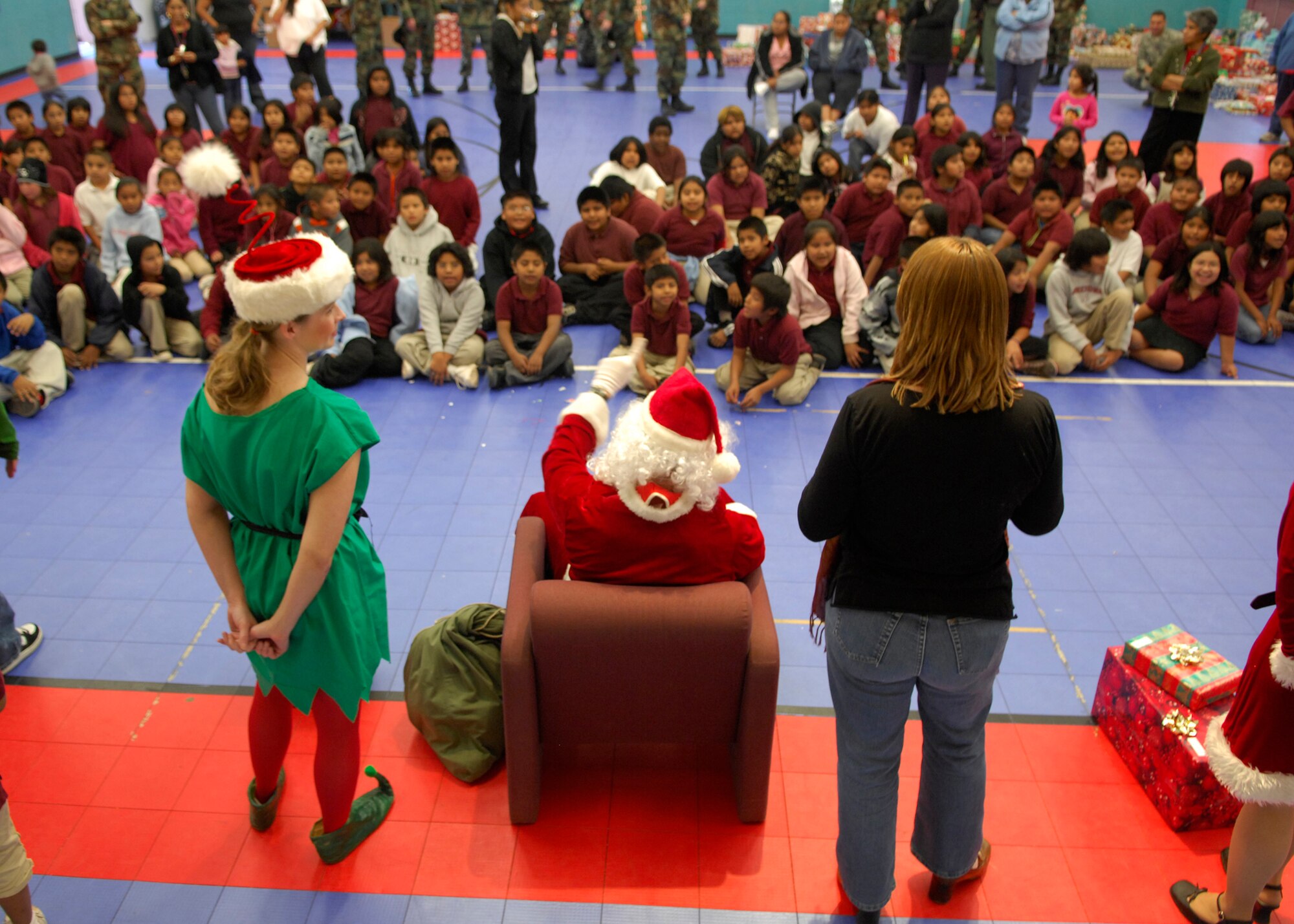 Santa played by Capt Christopher Johnson 355th Security Forces Commander, leads children in songs before handing out gifts donated from the 355th Wing during "Santa's in Blue" Thursday December 20th this is an ongoing event that has been occurring within the community many years. It involves Airmen from Davis-Monthan handing out Christmas presents to more than 400+ children grades K-3 of the Tohono O'odham Indian Reservation. For many of these children it will be the only gifts they receive for the holiday season. (U.S. Air Force Photo by Senior Airman Jesse Shipps)(Released)