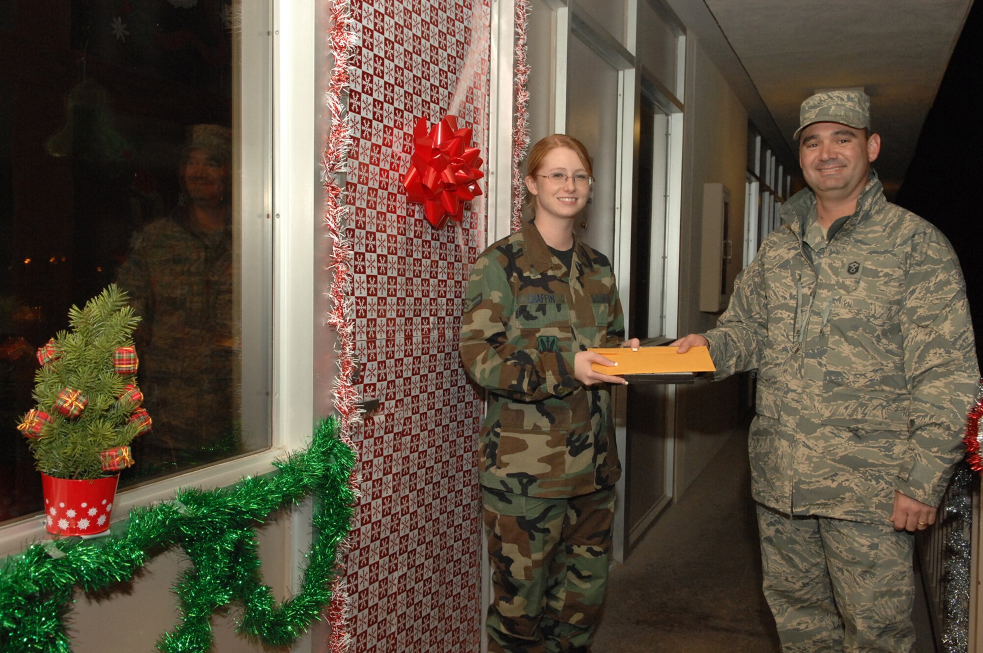 Airman 1st Class Tiffany Chaffin, 99th Comptroller Squadron, finance clerk, receives the third place award from Master Sgt. Stephen Ash, 99th Communications Squadron first sergeant, during the Nellis AFB Holiday Decorating Contest, Dec. 20. Prizes for the contest included $200 for first place, $100 for second place and $65 plus a Play Station 2 game for third place. (U.S. Air Force photo by Senior Airman Nadine Y. Barclay)